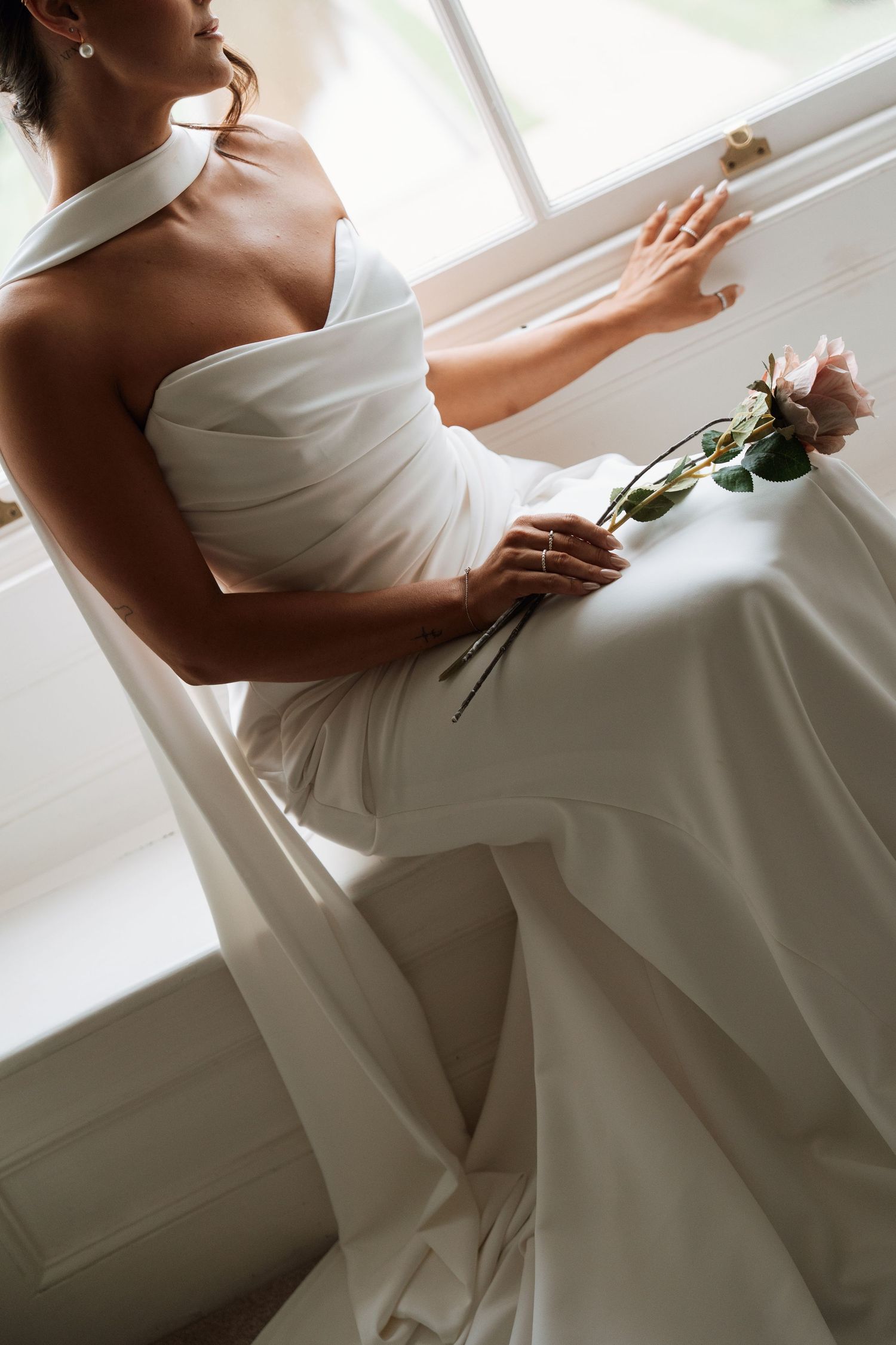 Elegant white wedding dress detail shot in natural window light.