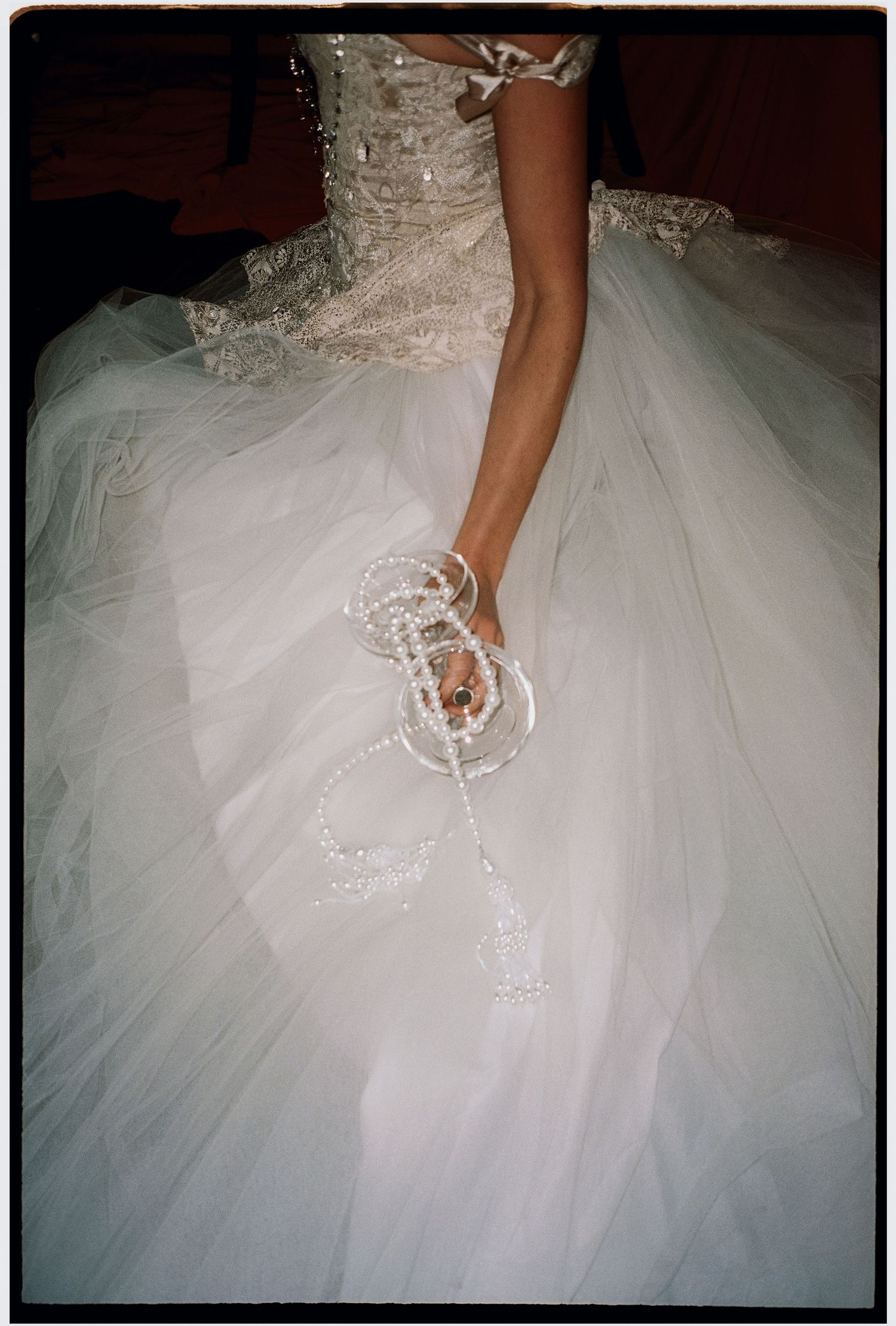 Close-up views of a flowing white tulle wedding dress with delicate pearl and lace details.