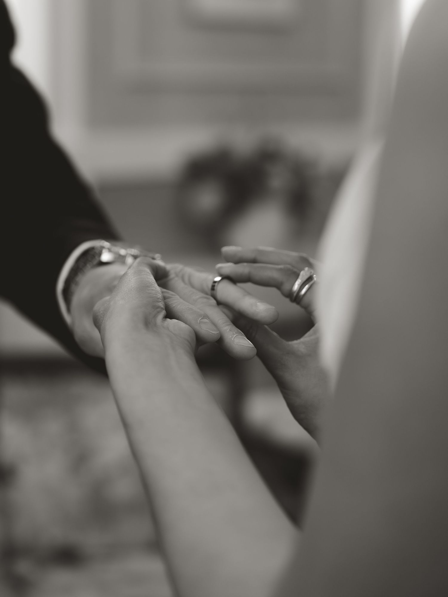 Black and white photo of a couple exchanging wedding rings during a marriage ceremony.