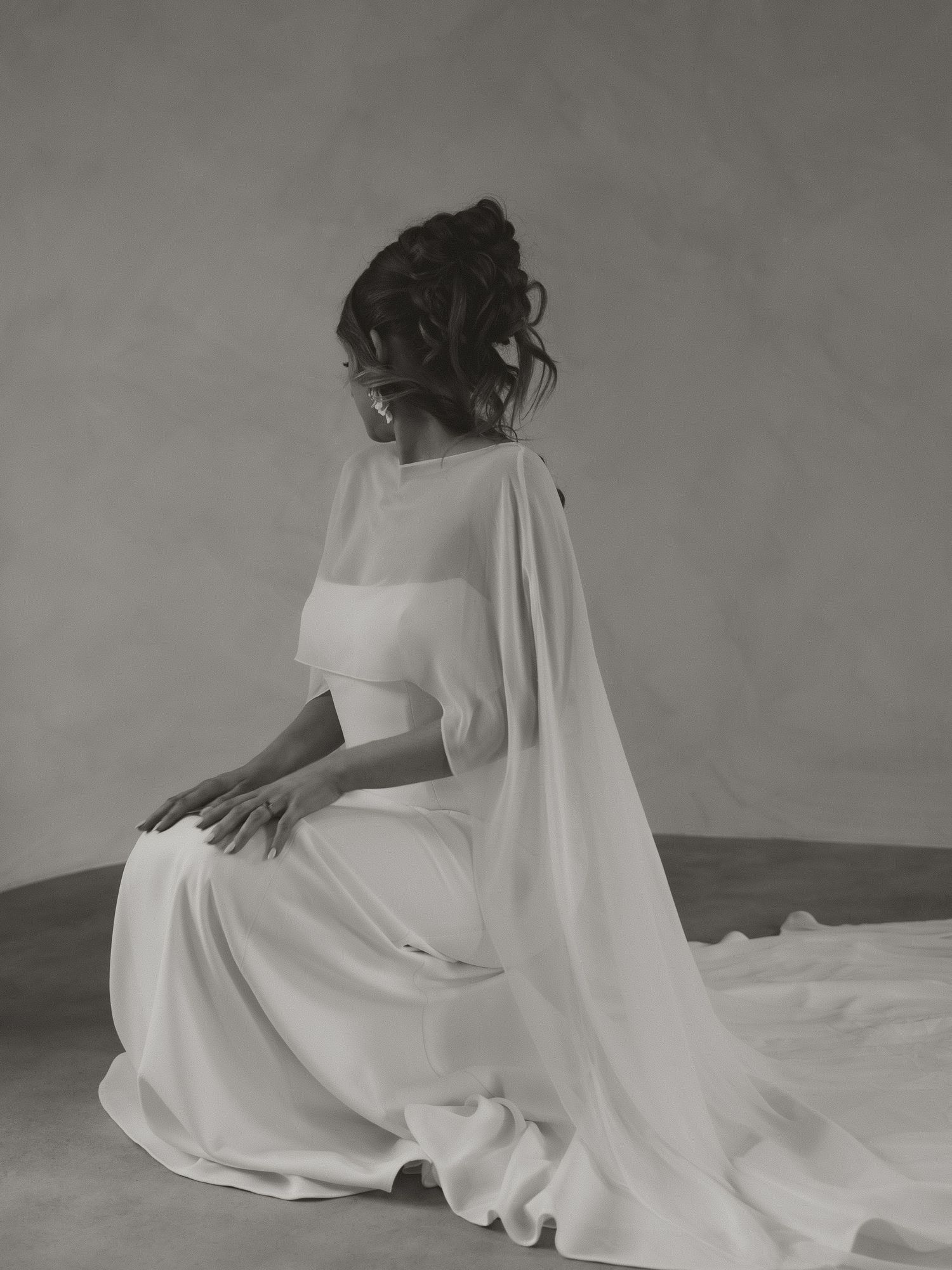 Artistic black and white portrait of flowing white wedding dress fabric in minimalist setting.