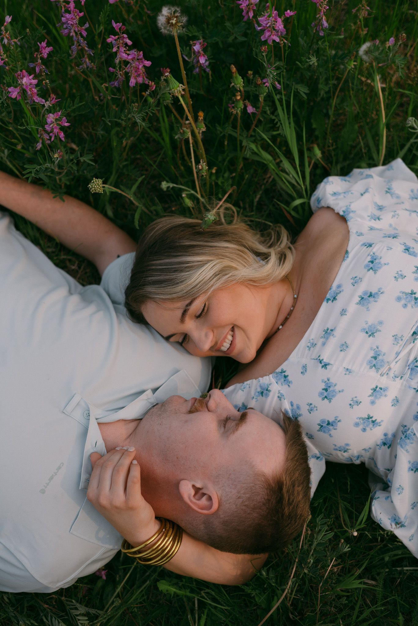Romantic moment of a couple laying in the grass surrounded by vibrant wildflowers near Fairbanks, Alaska.