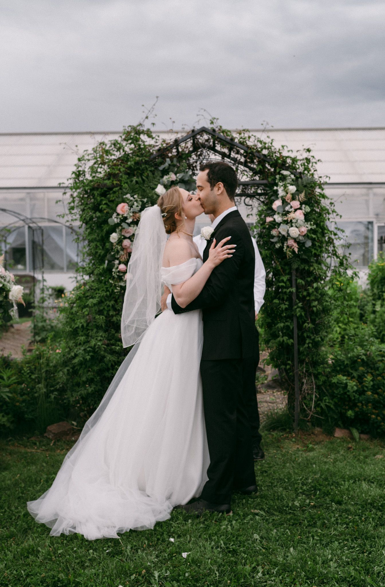A couple sharing a kiss during their ceremony, surrounded by flowers and loved ones in Fairbanks, Alaska.