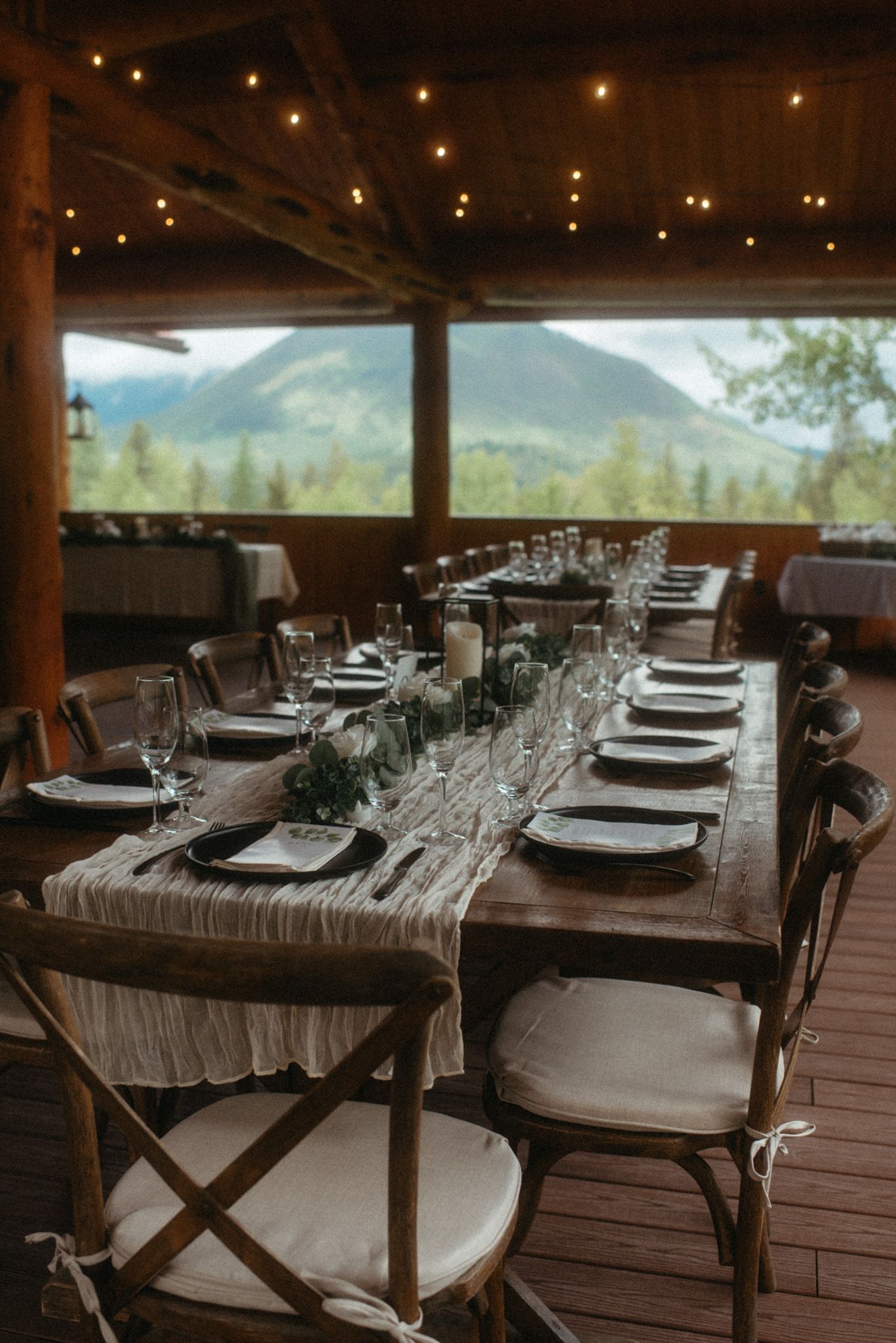 Elegant outdoor wedding setup with tables, plates, and glasses, overlooking the mountains at Glacier National Park, Montana.