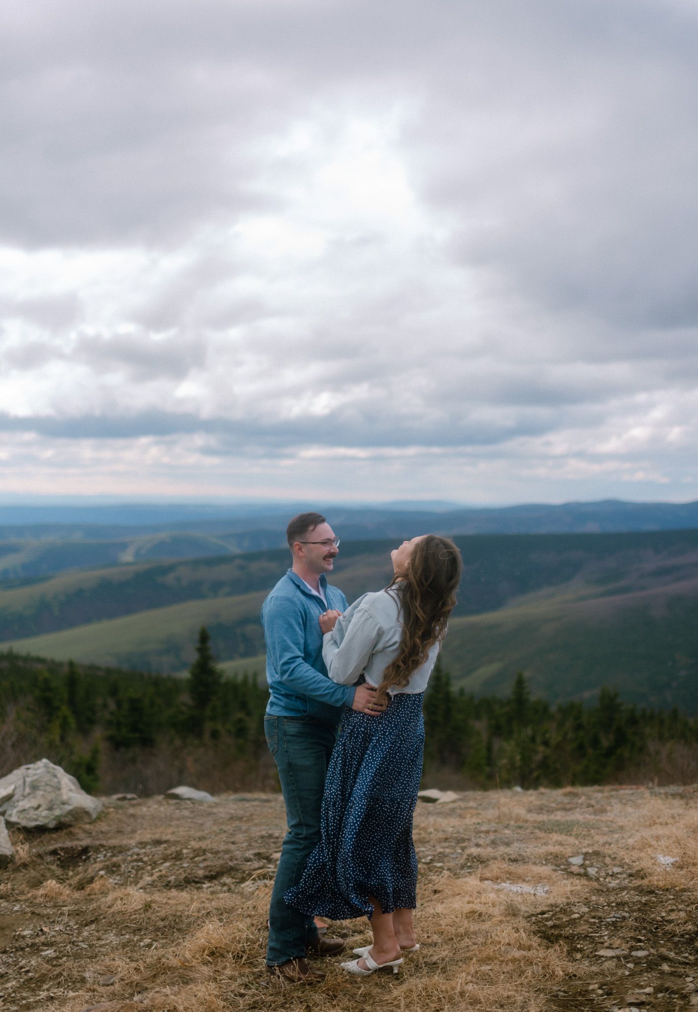 Engaged couple at their Fairbanks, Alaska engagement session with wide mountain landscape views, captured by an Alaska photographer.