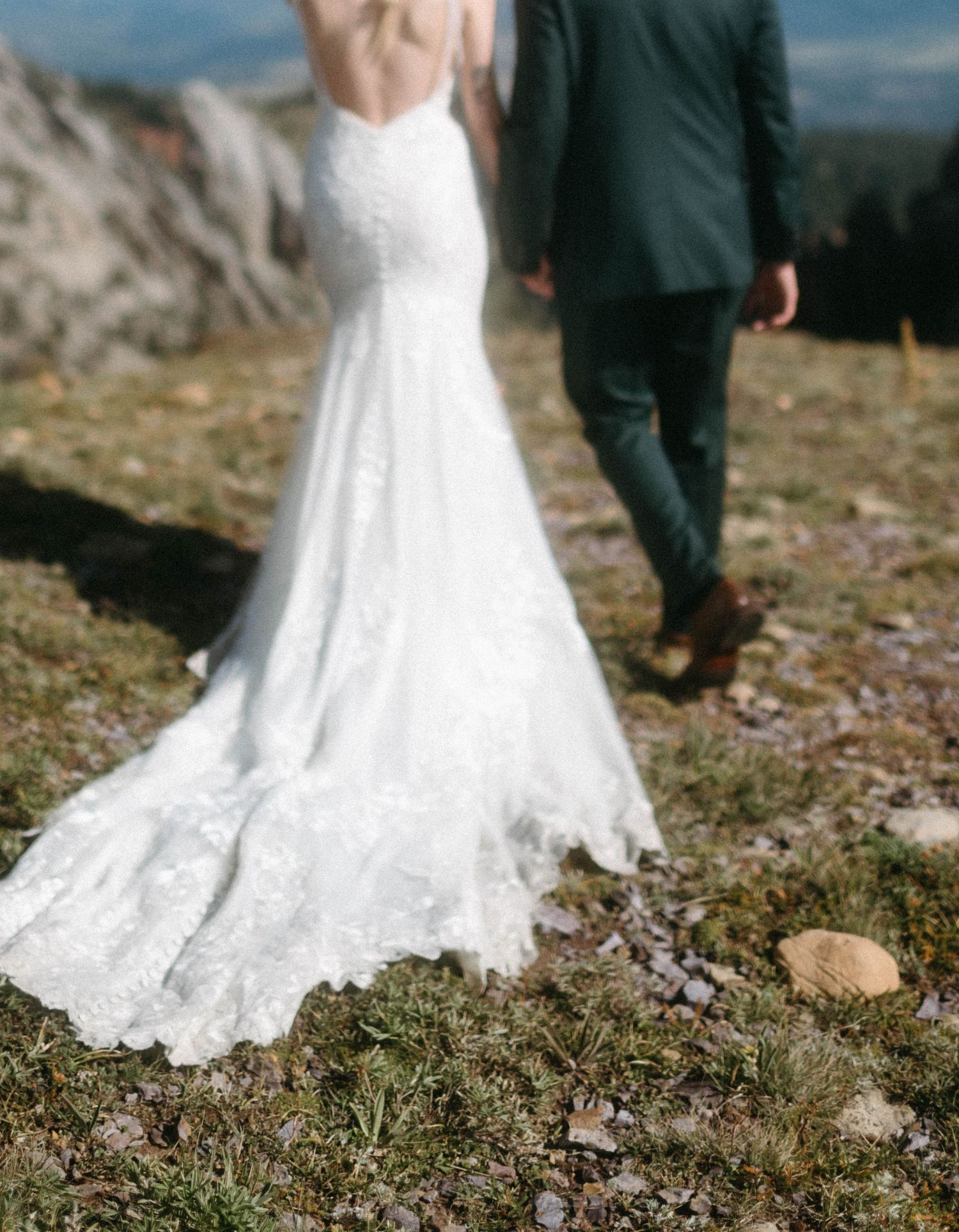 Detail shot of the bride’s wedding dress as she and her groom walk toward a stunning mountain backdrop in Bozeman, Montana