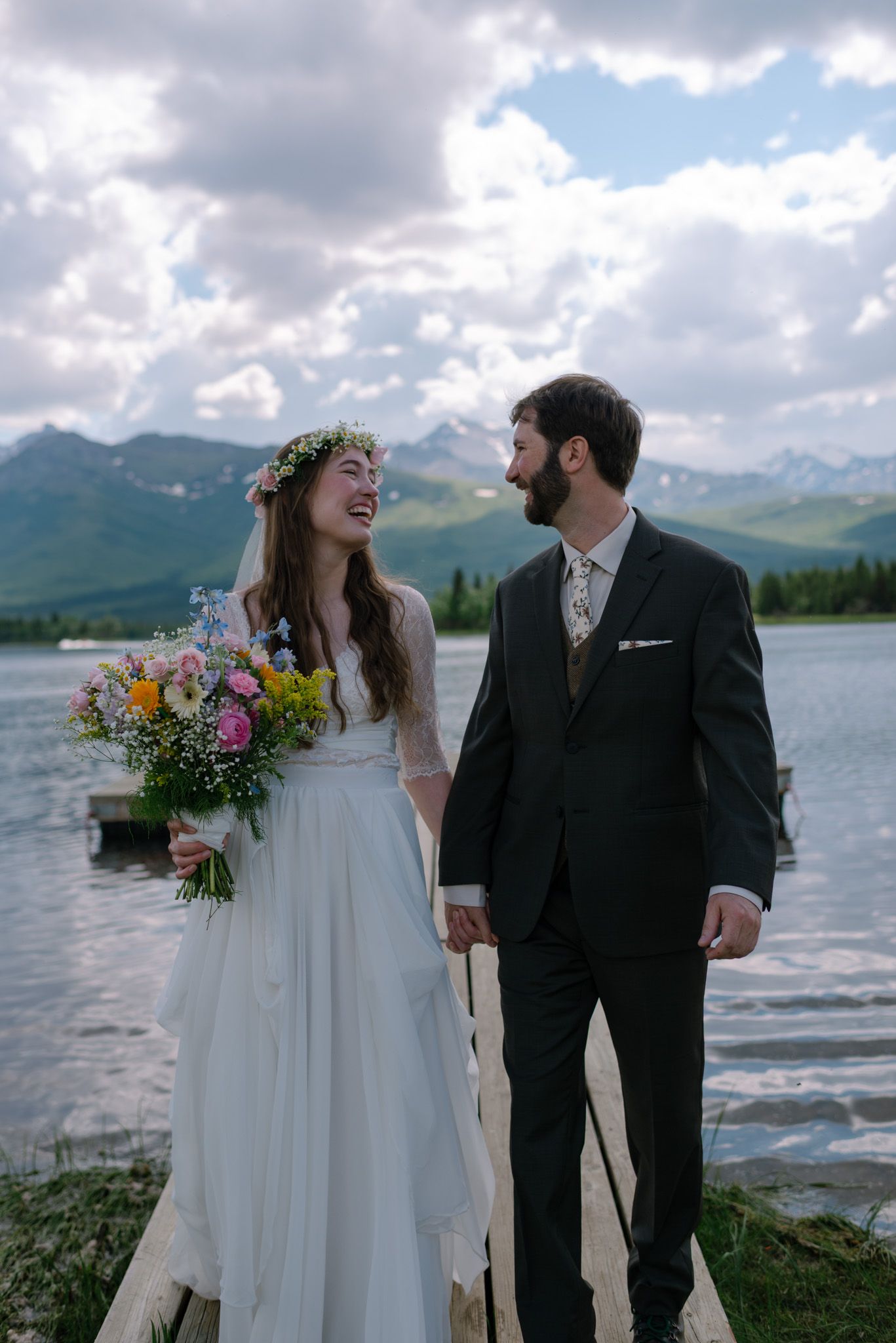Joyful newlyweds sharing a moment together during their lakeside Alaska wedding with mountain views in the background.