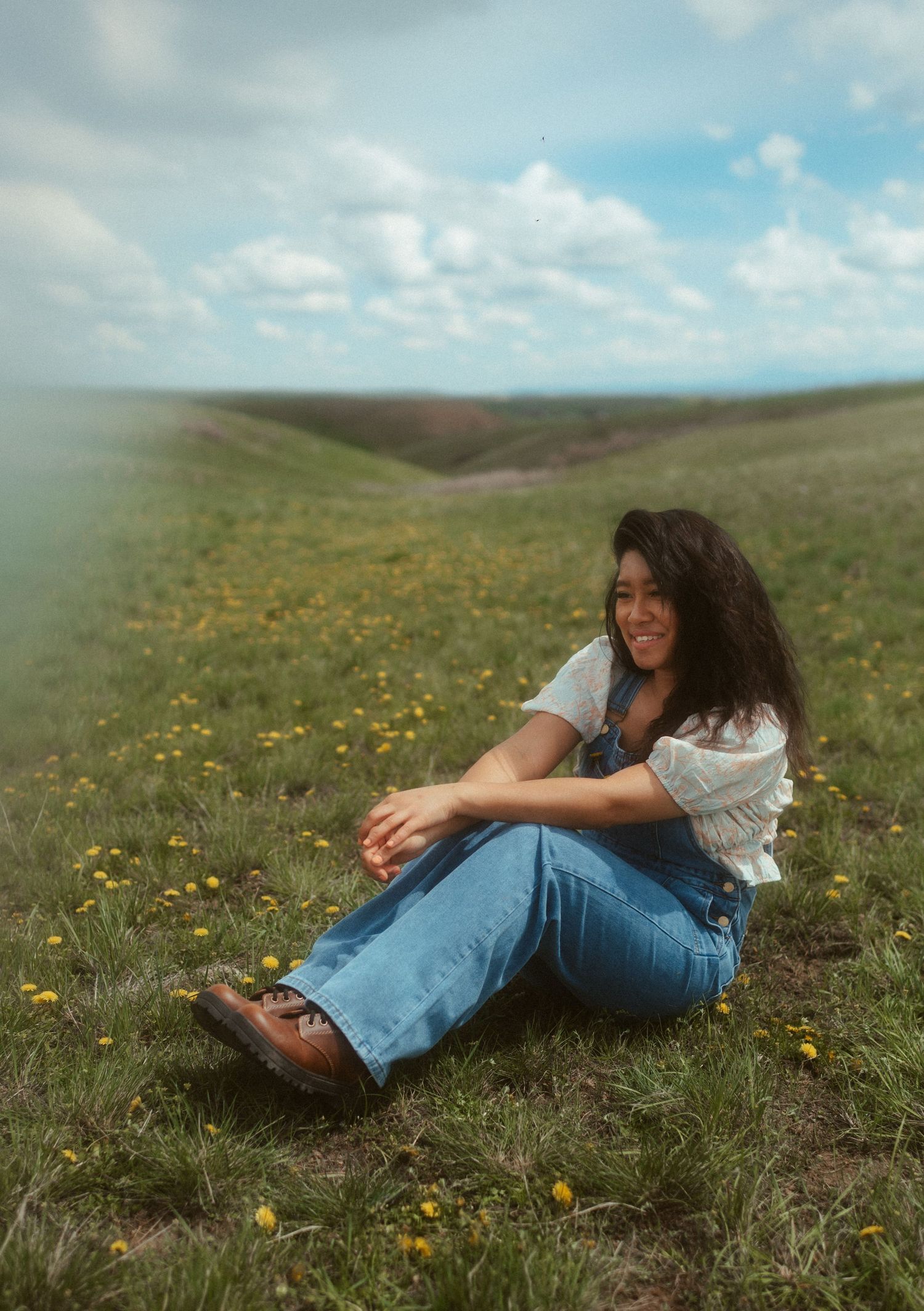 Self-portrait of a wedding photographer surrounded by dandelions and soft hills under bright sun in Great Falls, Montana.
