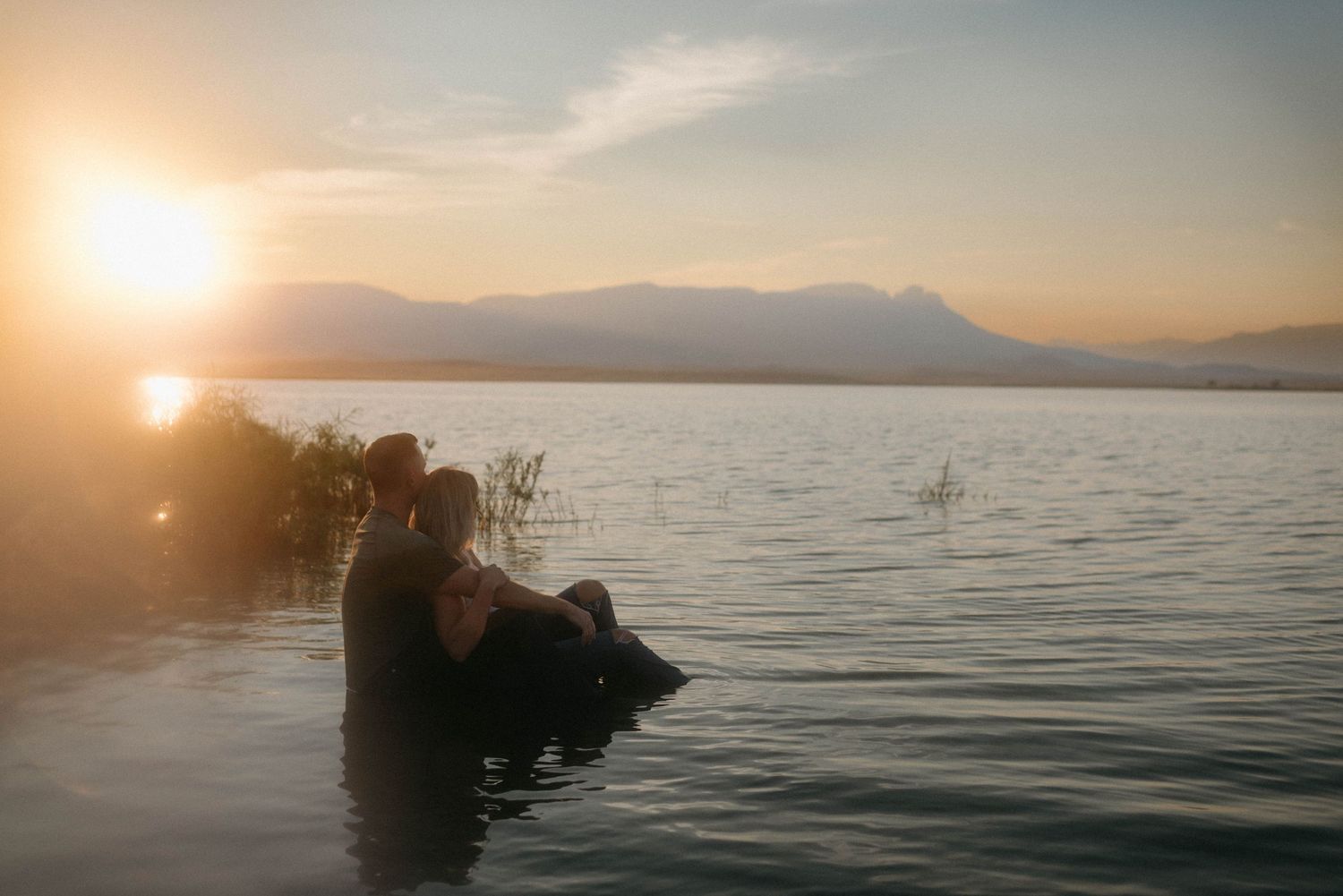 Couple sharing an intimate moment on the water near a cascade in Great Falls, Montana.