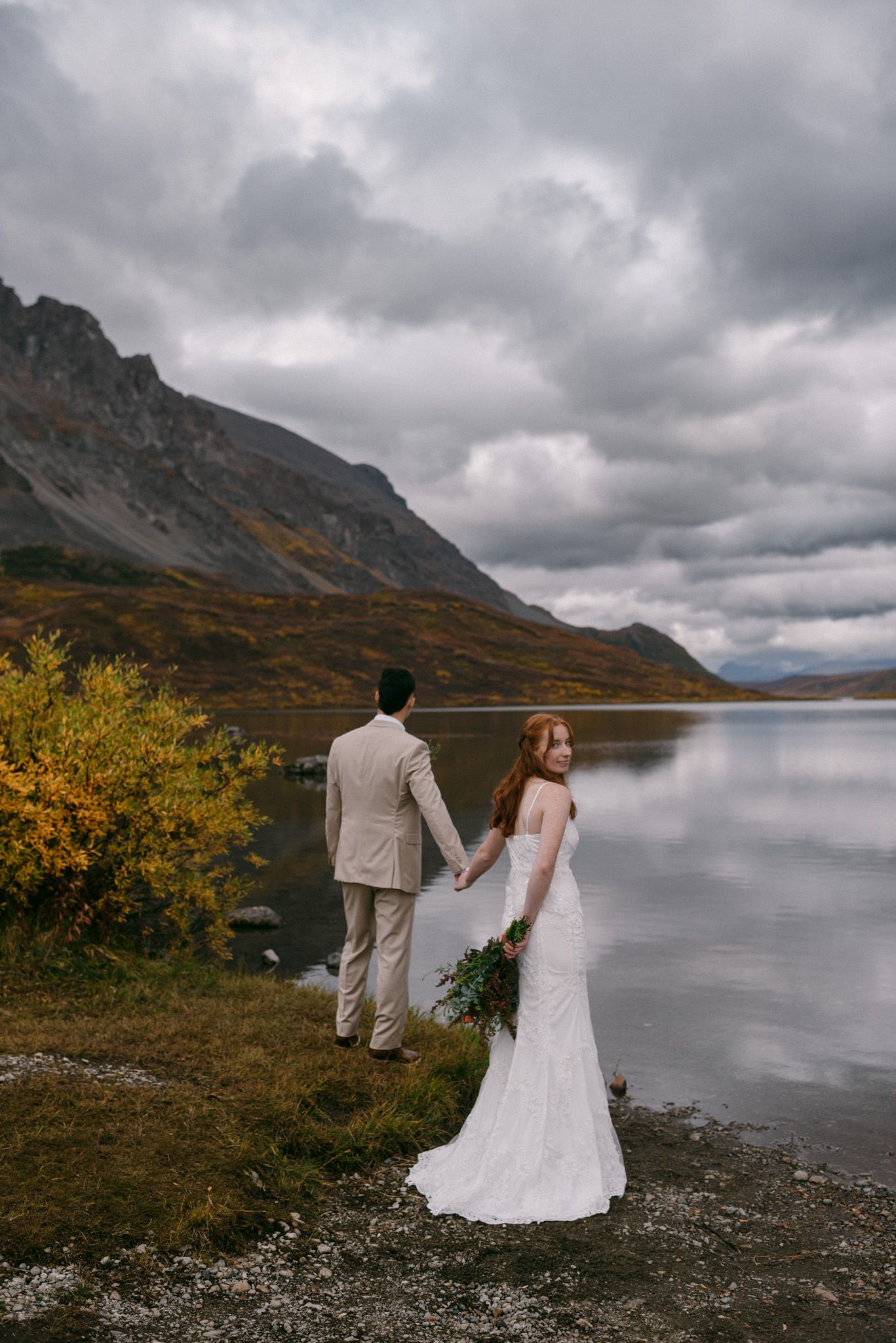 Intimate wedding portrait of bride and groom in Alaska mountains by a flowing river.
