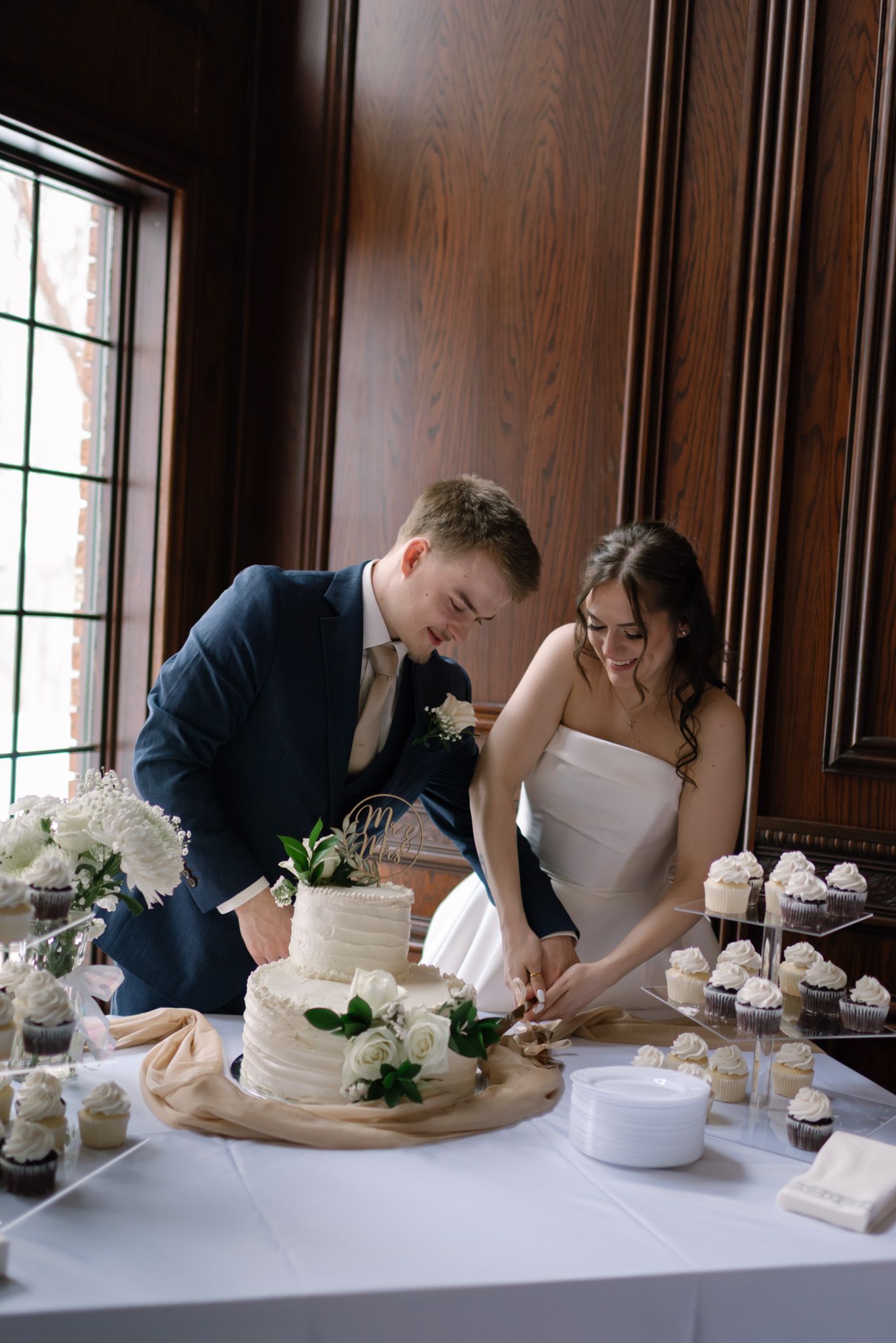 Captured a bride and groom cutting their wedding cake together during their wedding celebration in Fairbanks, Alaska.