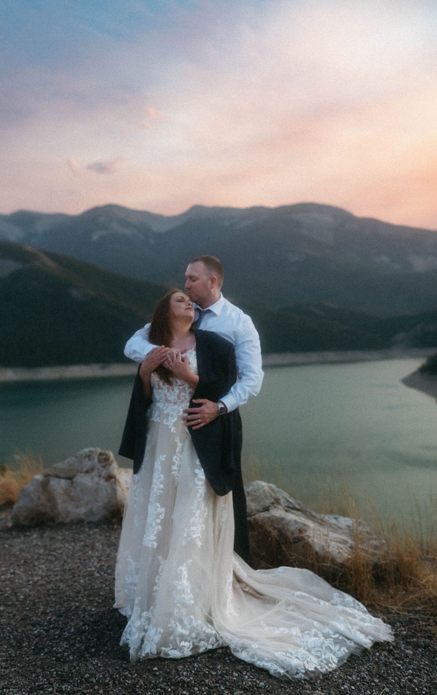 Newlyweds renewing their vows at sunset on a mountaintop near Great Falls, Montana, surrounded by mountains and vibrant colors.