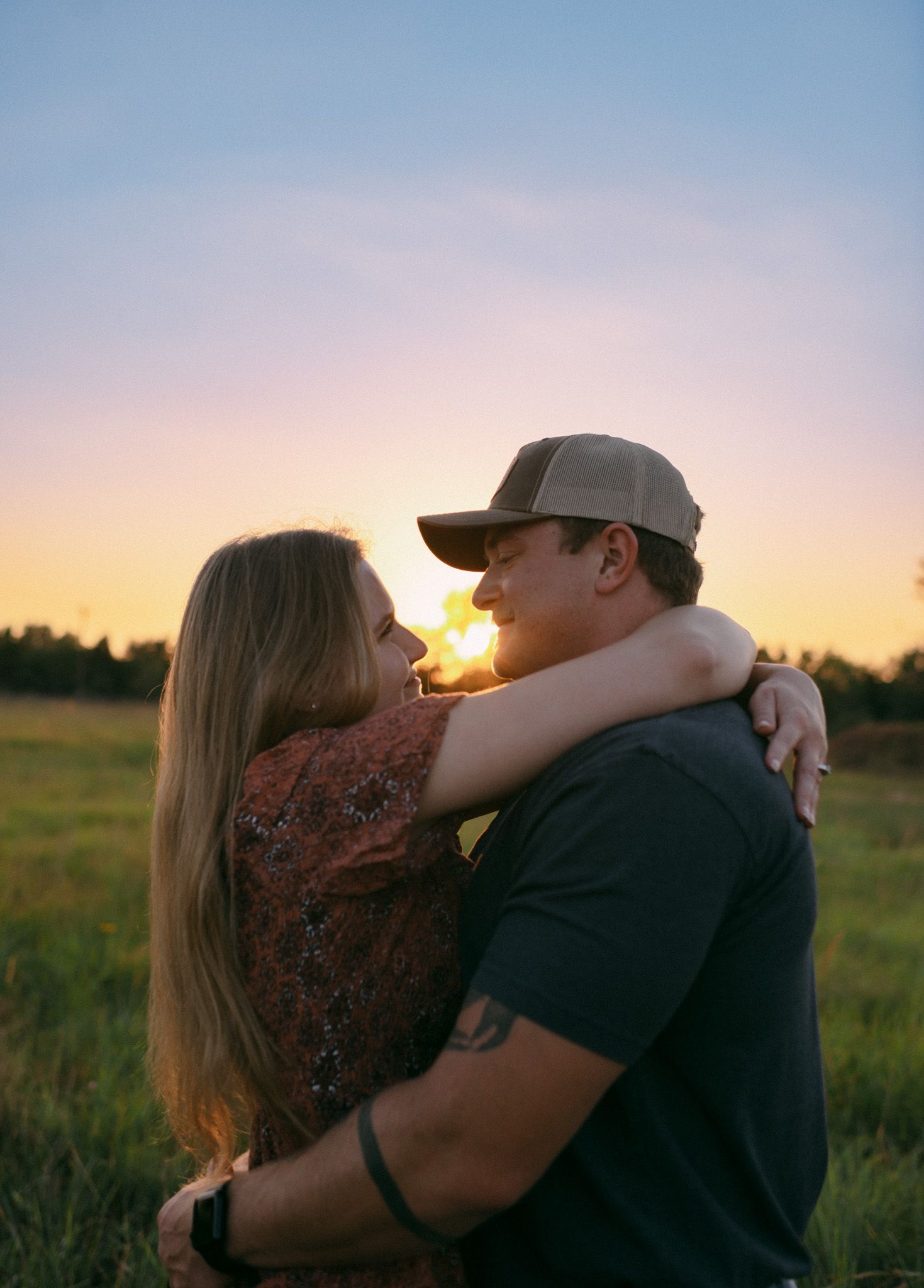Engaged couple looking into each other’s eyes, capturing a romantic moment during a sunset engagement session in Wichita, Kansas.