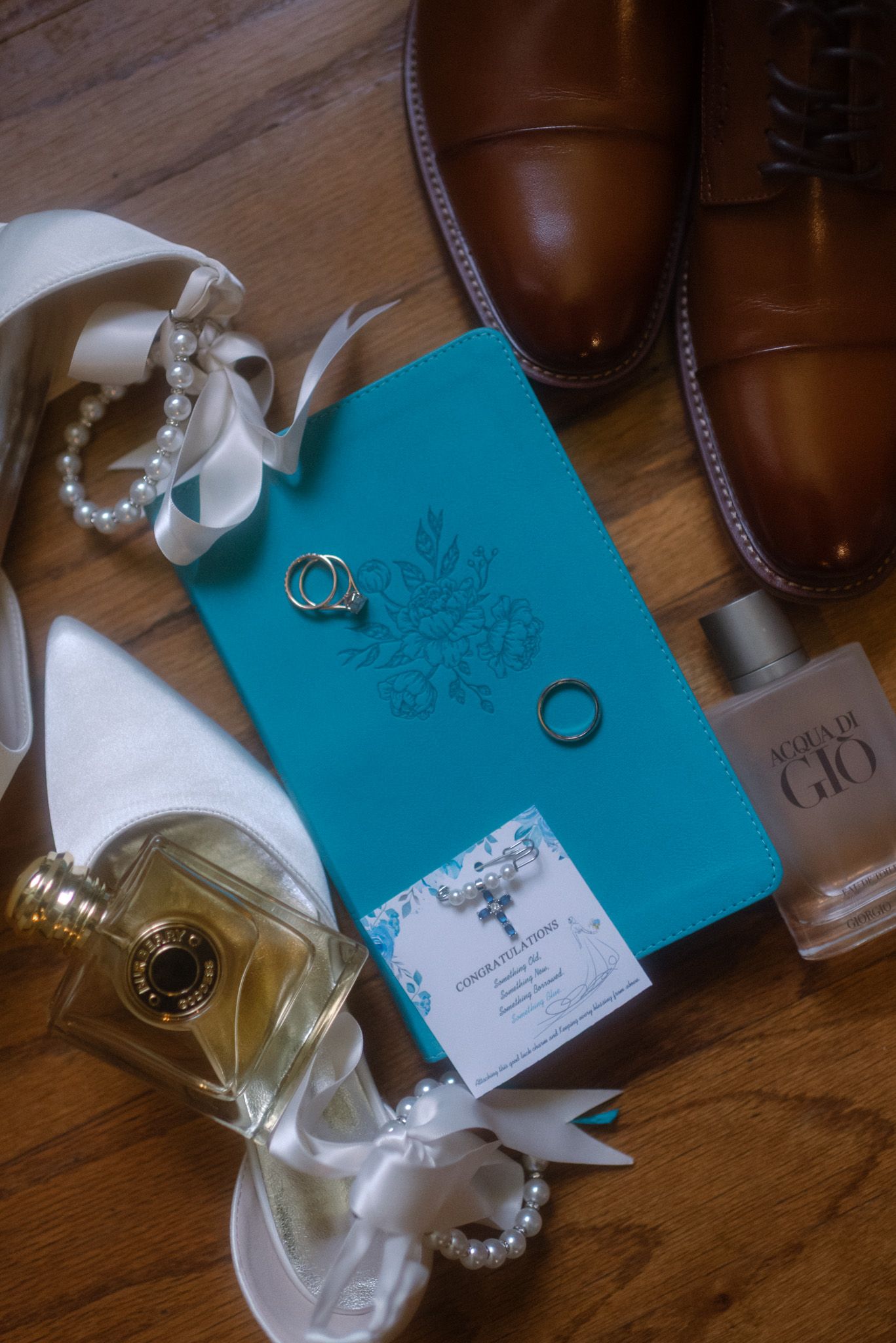 Elegant wedding detail shot featuring rings, bridal shoes, perfume, and notebook highlighting personal wedding story elements.