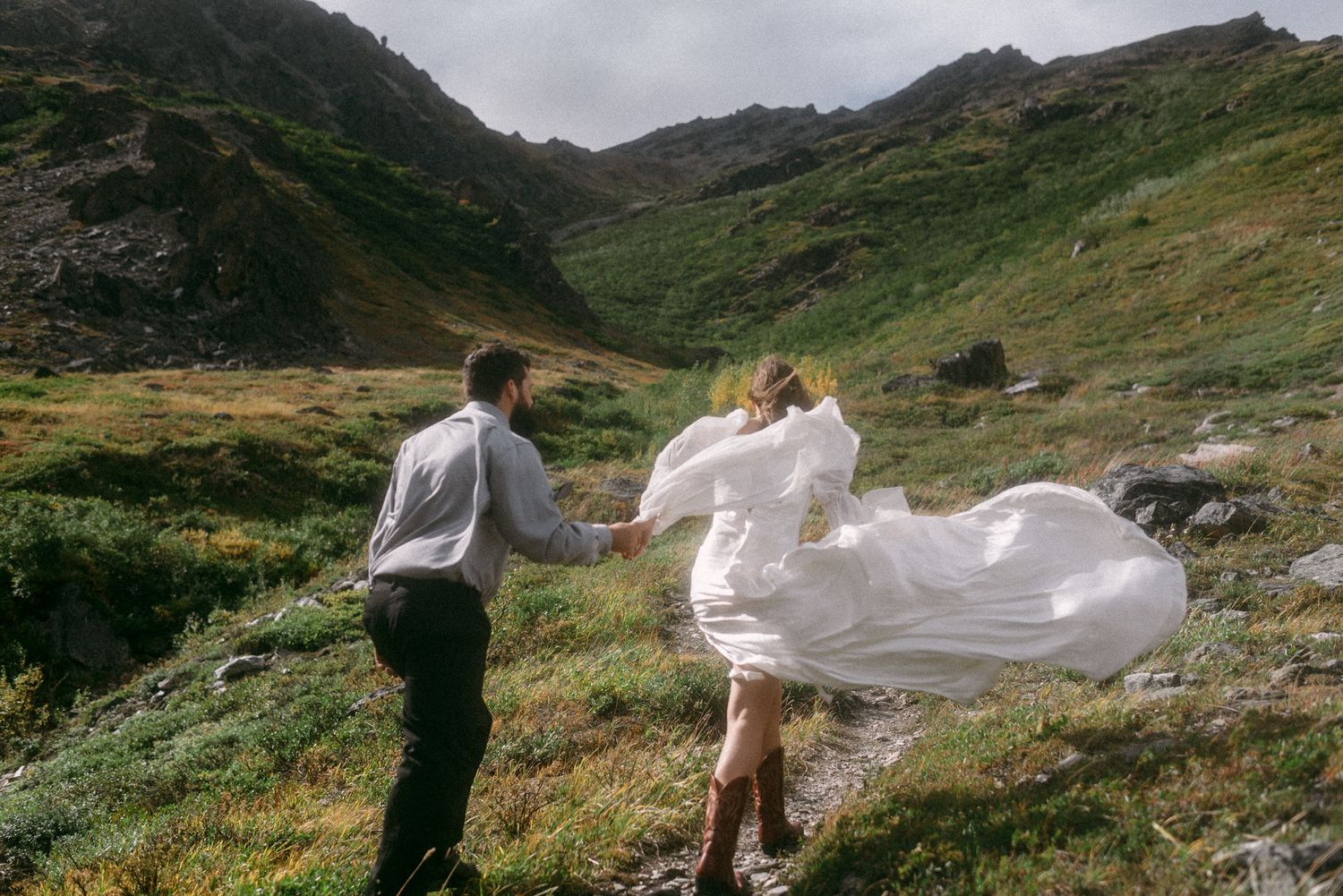 A couple hiking to the top of a mountain in Denali National Park, Alaska, celebrating their elopement day in windy weather.