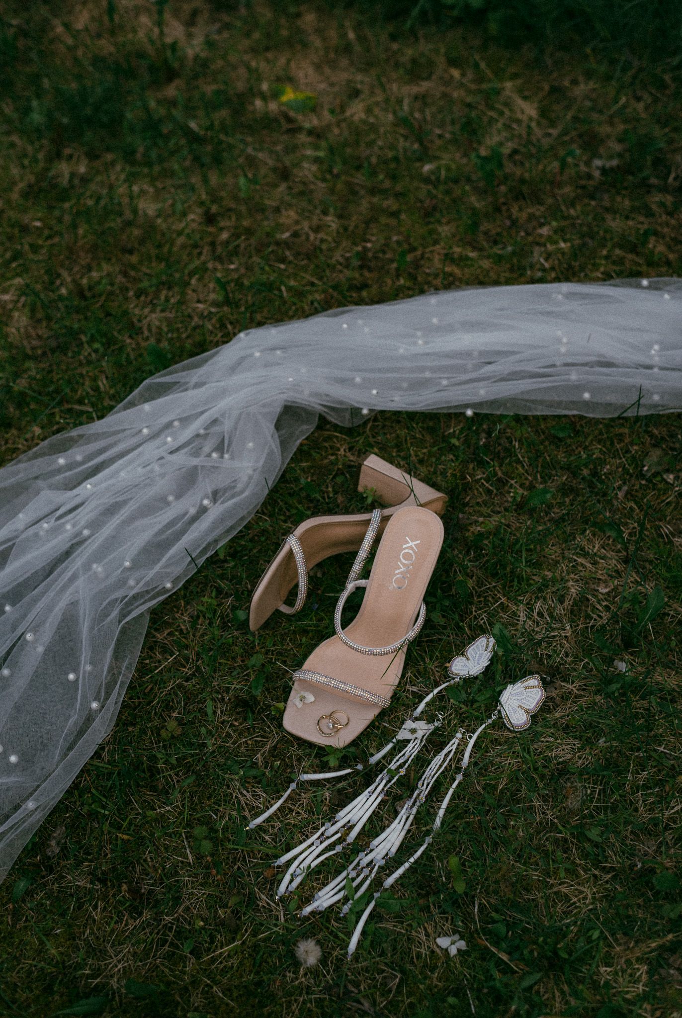 Flat lay of the bride’s wedding details—shoes, jewelry, and veil—captured on lush grass at Midnight Sun Golf Course, Fairbanks, Alaska.