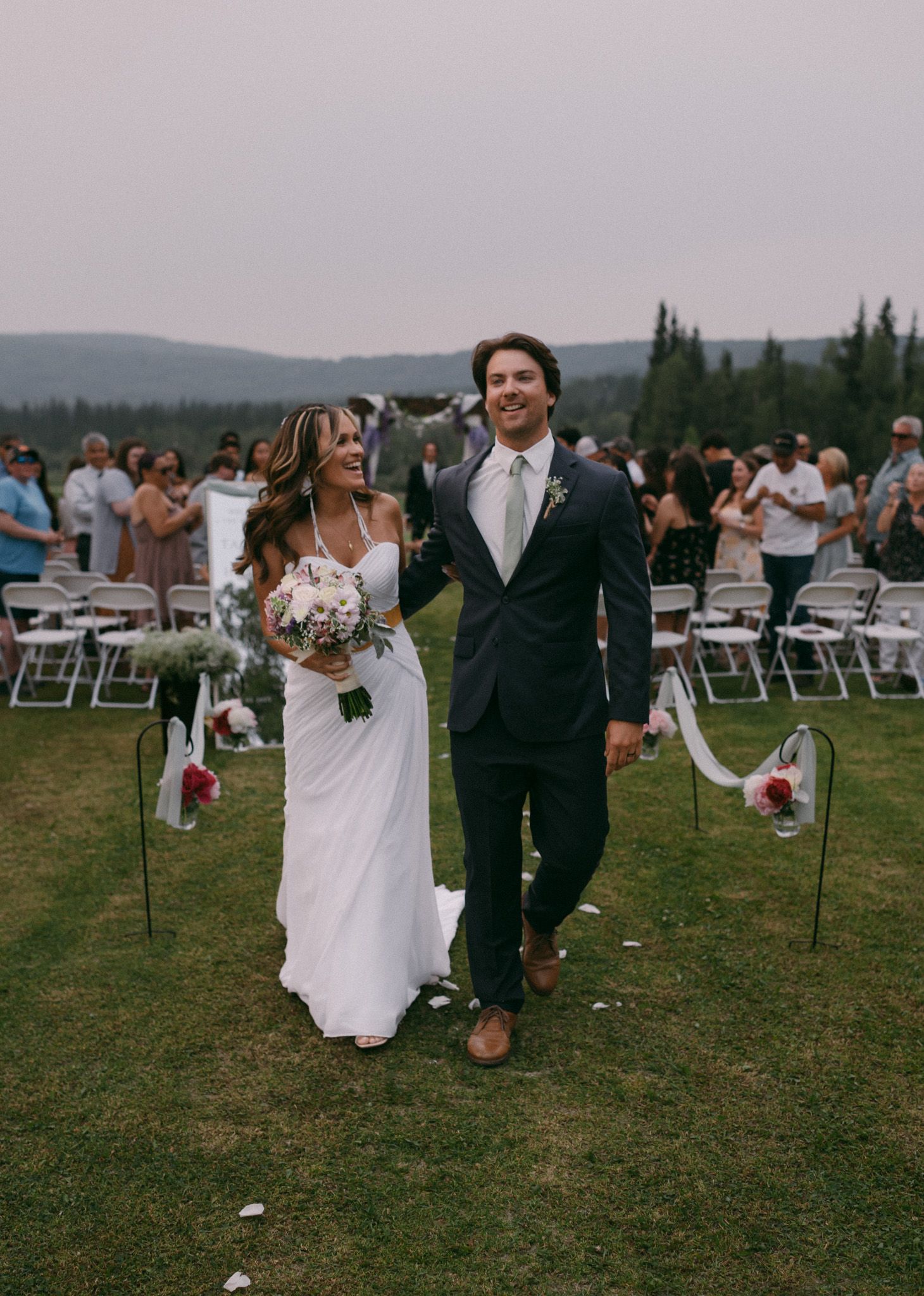 Bride and groom walking down the aisle together in Fairbanks, Alaska while friends and family celebrate their wedding.