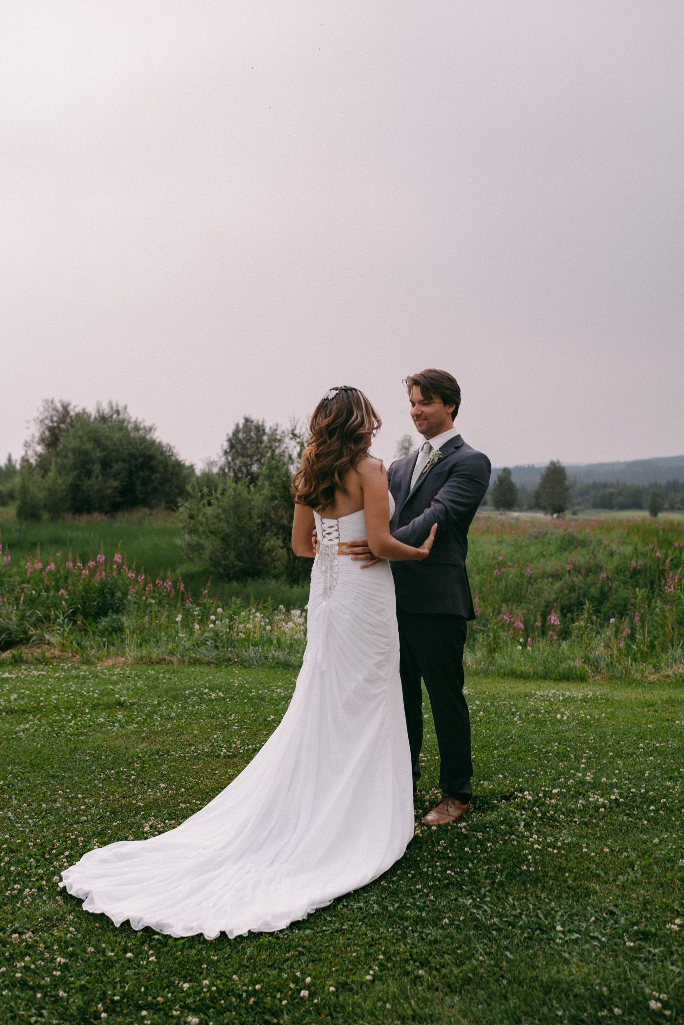 Bride and groom sharing their first look surrounded by wildflowers in Fairbanks, Alaska on their wedding day.