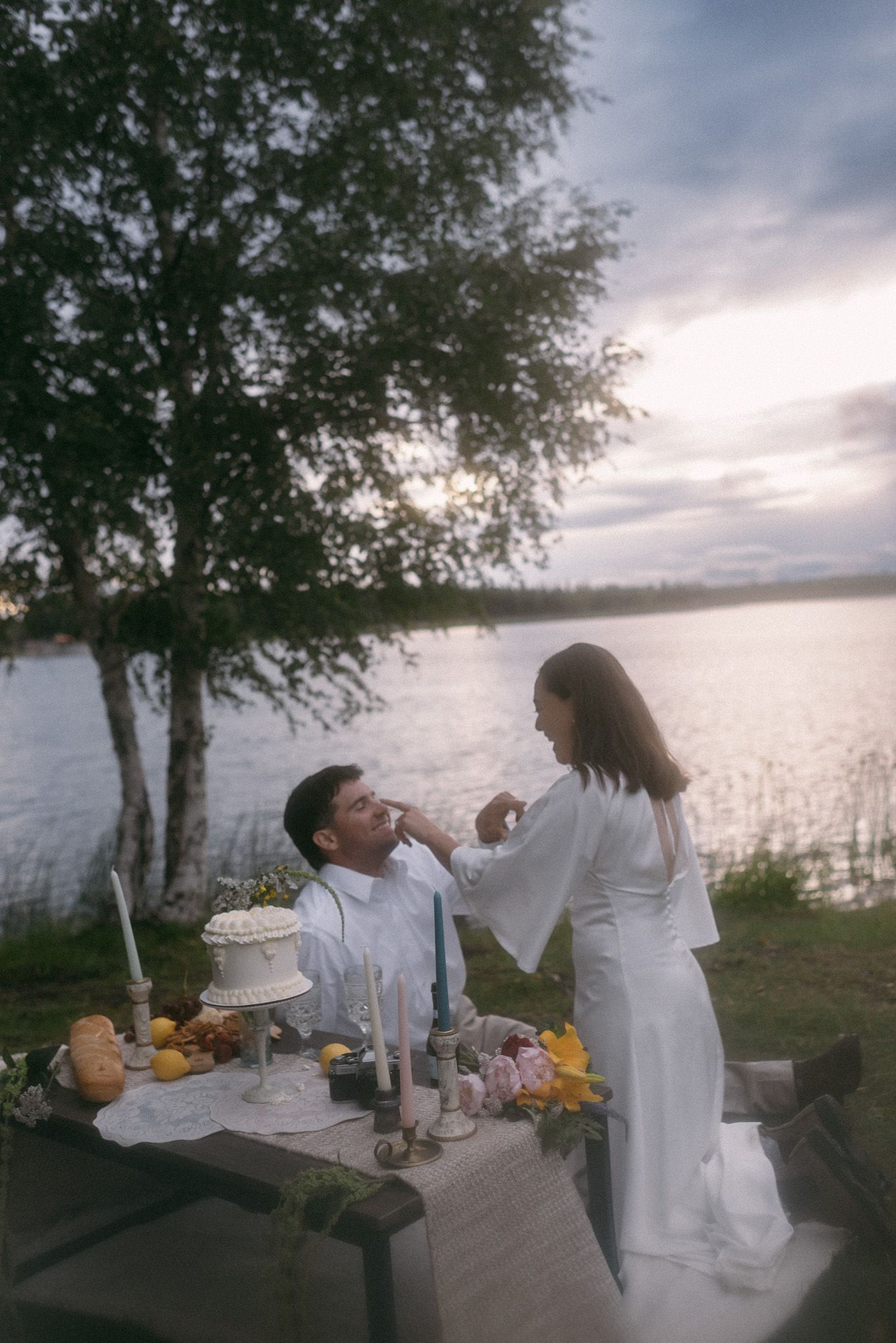 Bride and groom sharing cake on their elopement day during sunset in Alaska
