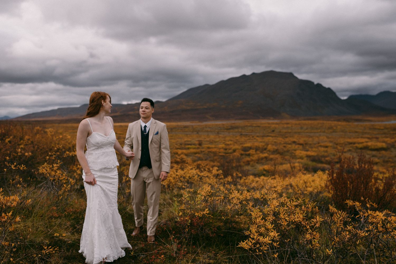 Bridal couple celebrating their elopement in Denali National Park, Alaska, surrounded by vibrant autumn colors in September.
