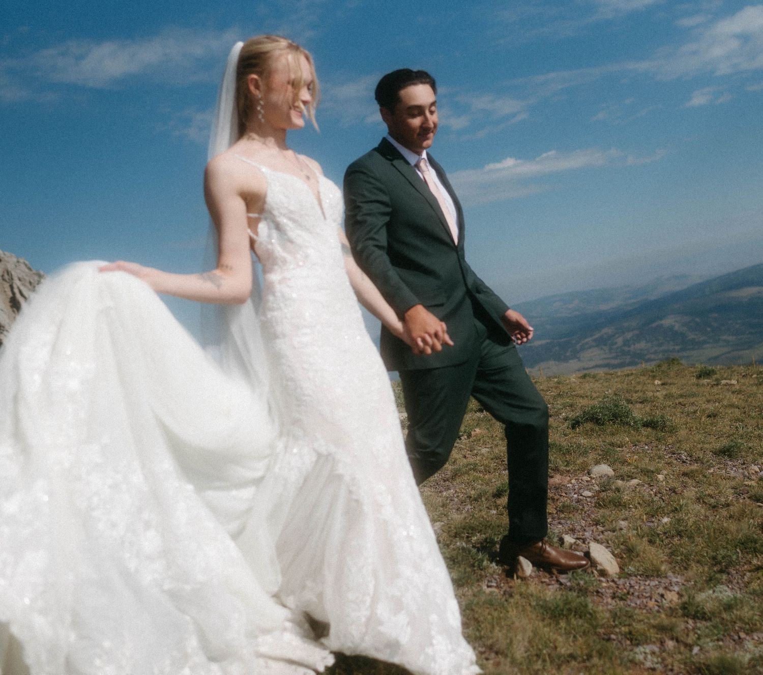Bridal couple hiking down a mountain after their Bozeman, Montana elopement, celebrating on a sunny wedding day.
