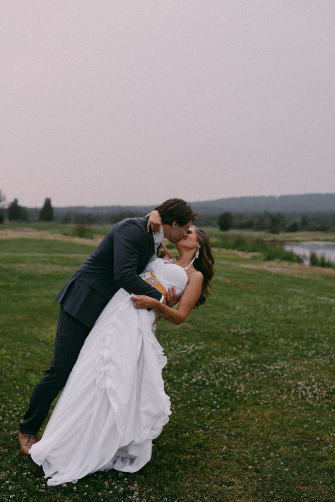 Couple sharing an intimate moment with the groom dipping the bride for a kiss on a scenic golf course in Fairbanks, Alaska.