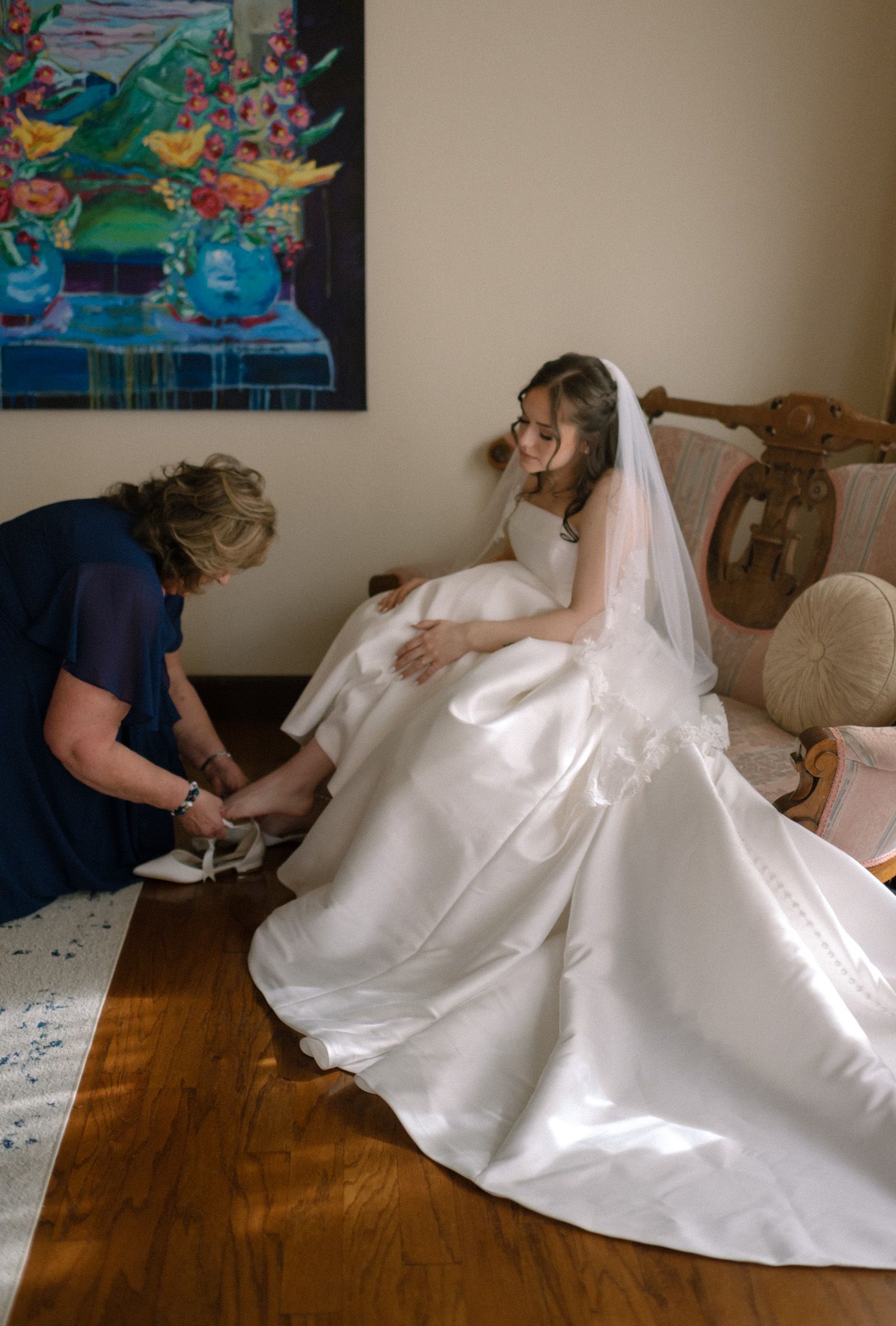 Bride getting ready as her grandmother lovingly helps her into her wedding shoes before the ceremony at Huffman Manor in Fairbanks, Alaska.