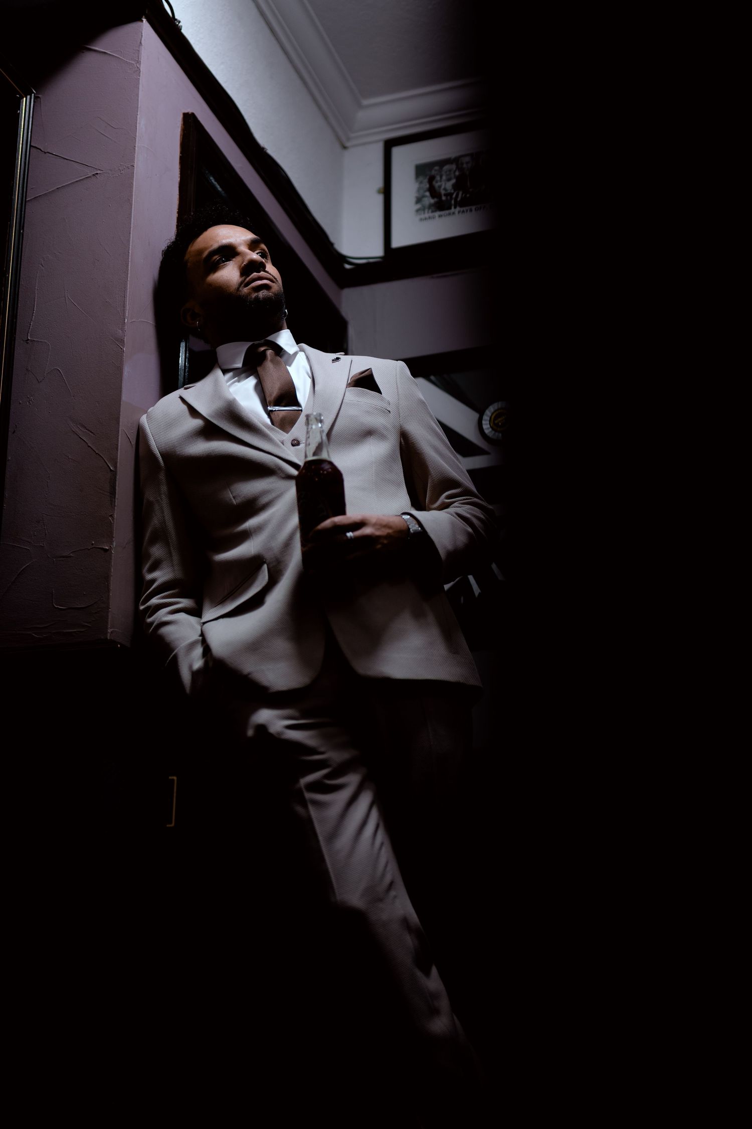 A person in a white suit poses dramatically against a dark background in a series of moody portrait shots.