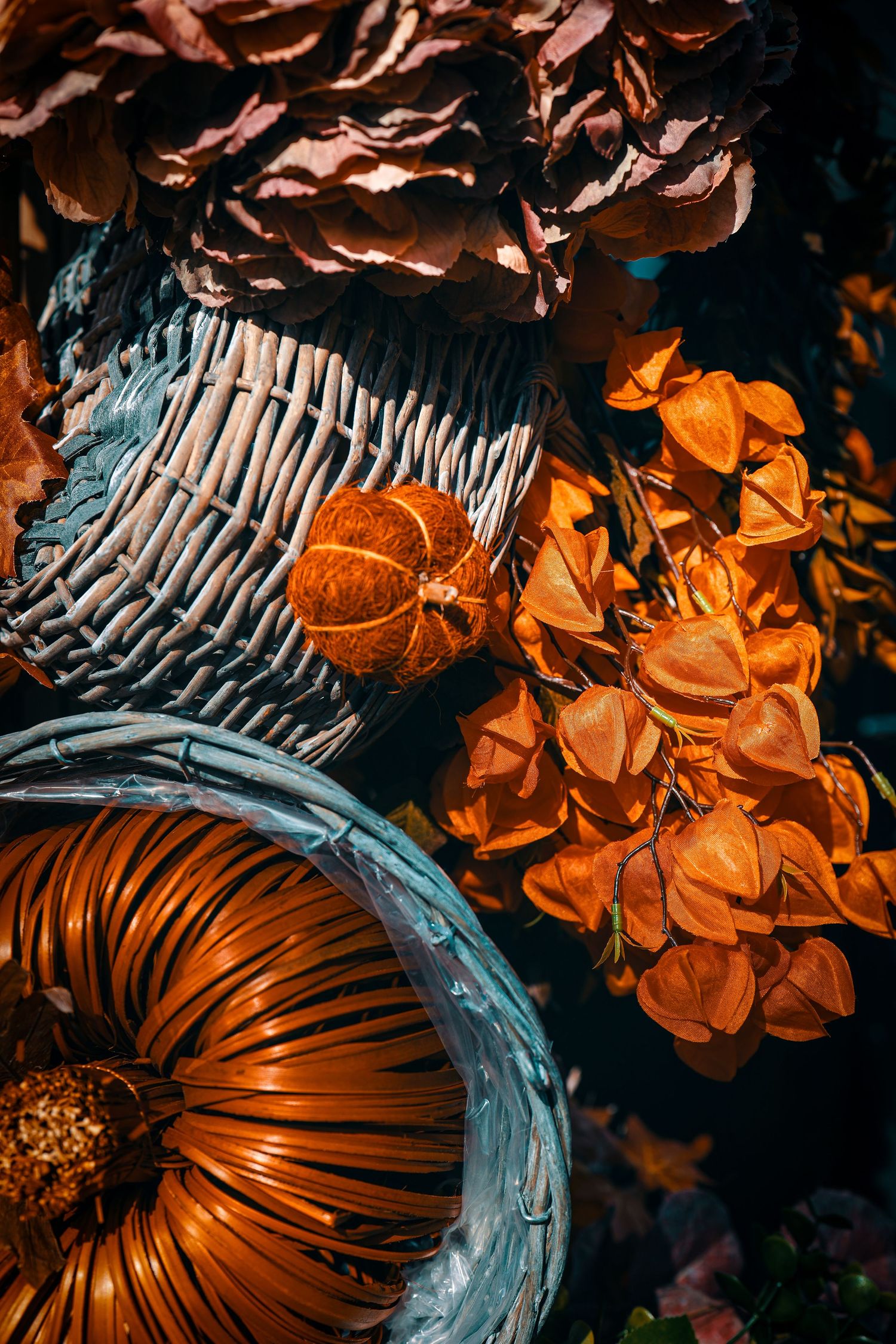 Rustic autumn still life with orange pumpkins and dried flowers in woven baskets with moody dark lighting.