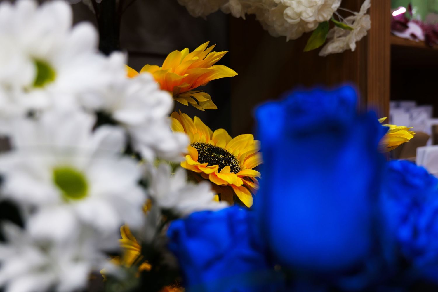 A bright yellow sunflower stands out against a blurred background of vibrant blue and white colors.