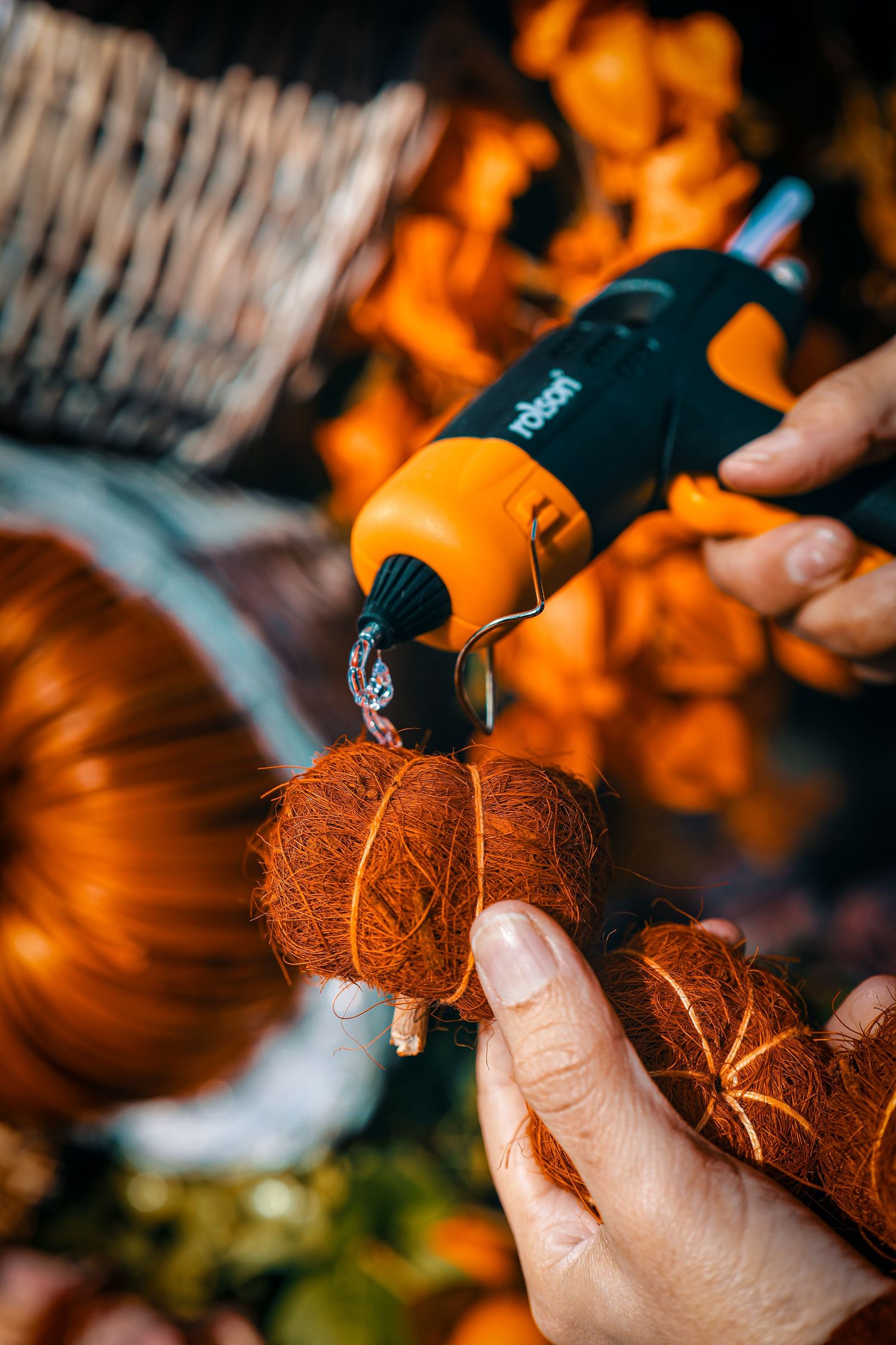 Close-up of hands carving intricate designs into an orange pumpkin with a specialized carving tool.