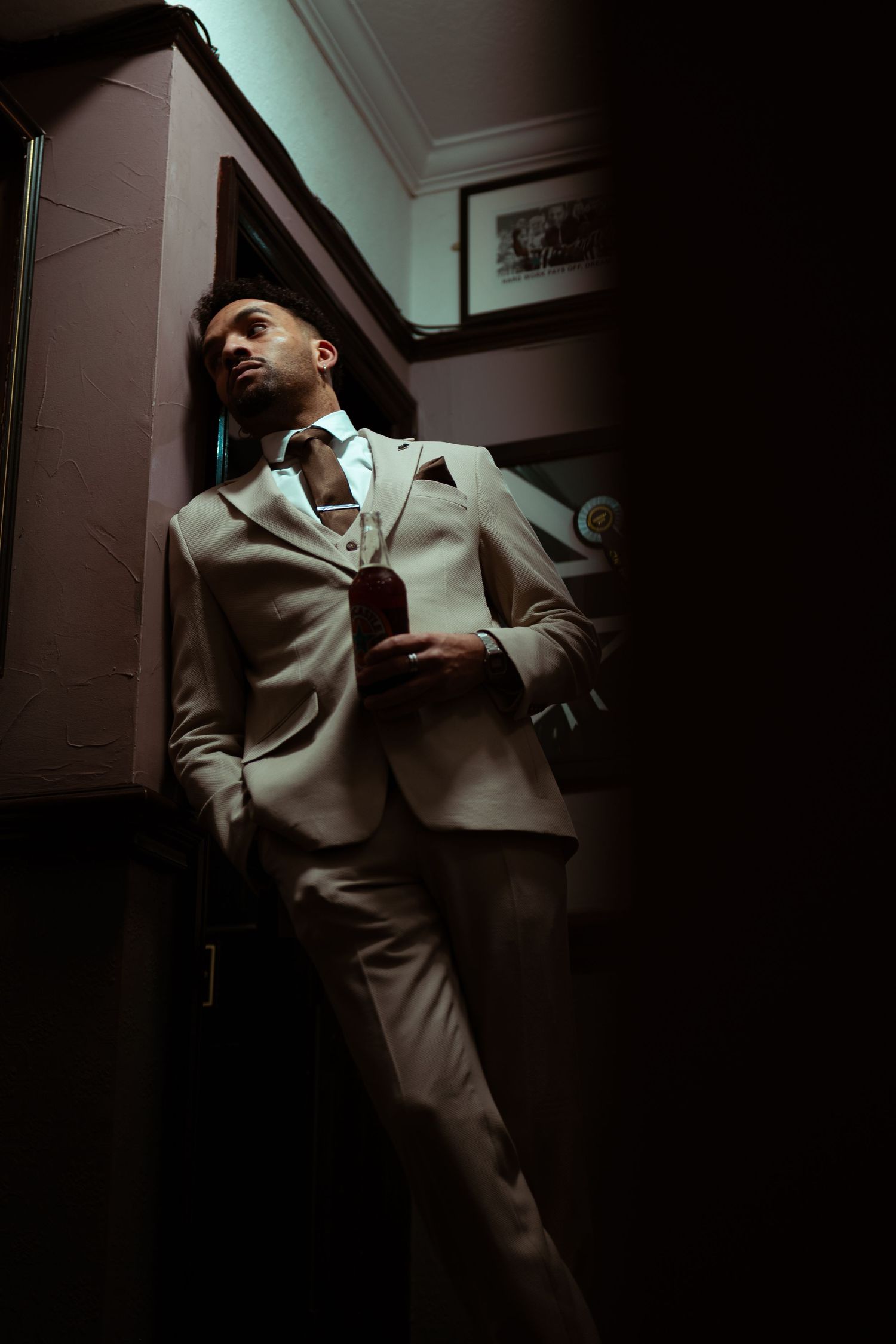 A series of moody black and white photos showing a person in a light-colored suit against a dark background.