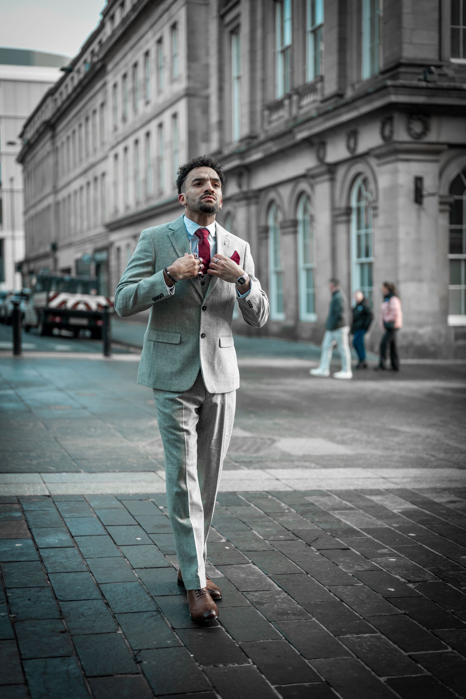 A person in a mint green suit and white shirt strikes dynamic poses on a cobblestone street against an urban backdrop.