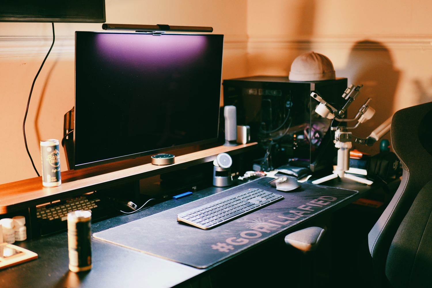 Modern computer setup with multiple monitors and peripherals on a wooden desk in a dimly lit room.