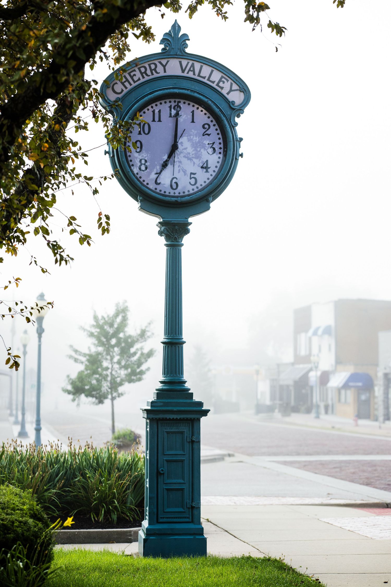Ornate green street clock in Cherry Valley town square on a foggy morning.