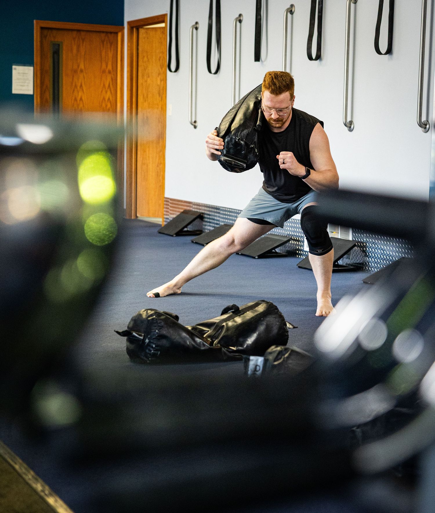 Athletic man performing a sandbag exercise during an intense gym workout session.