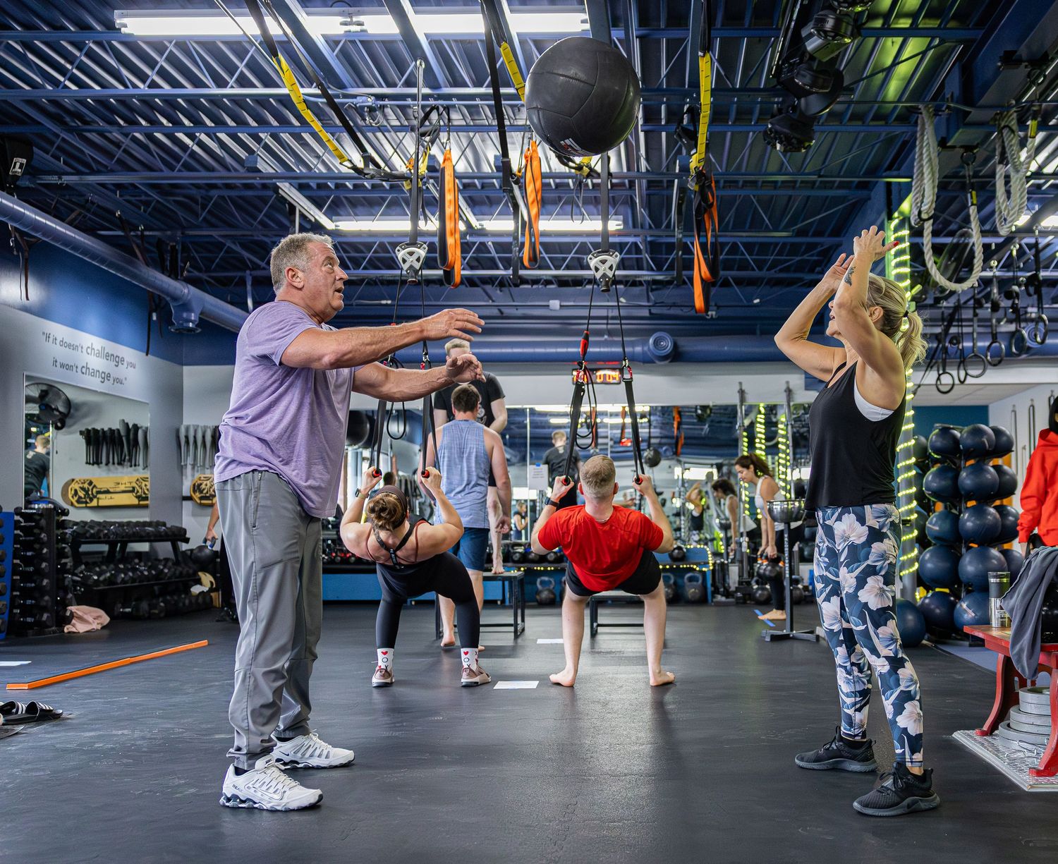 A fitness instructor guides a group workout class in a modern gym facility.