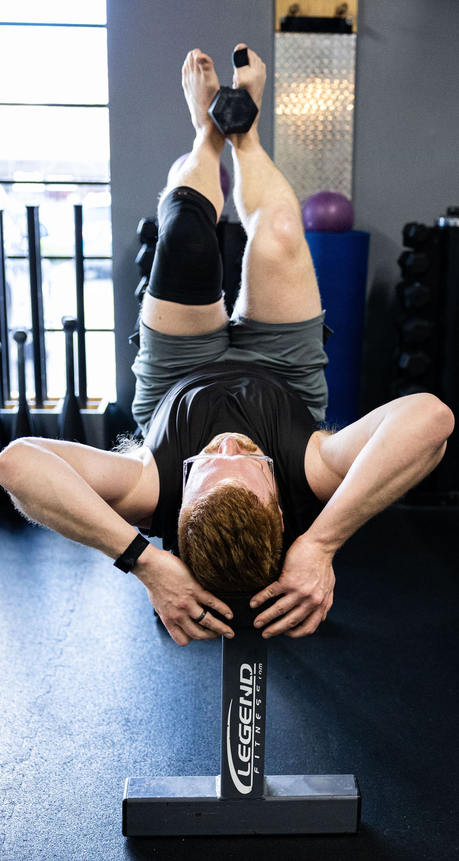 Athlete performing an inverted exercise on a Legend Fitness bench in a gym.