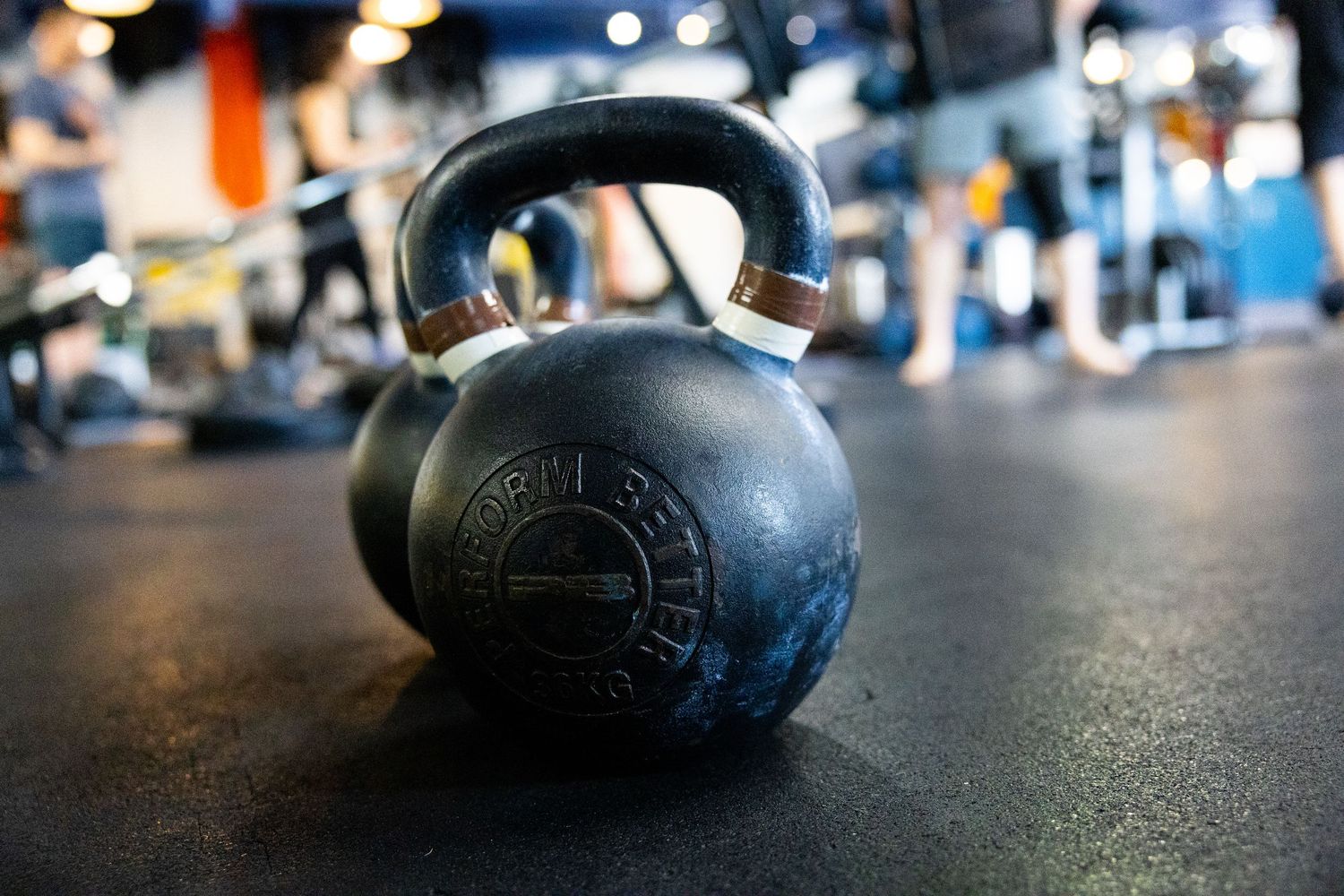 Close-up of a heavy black kettlebell on a gym floor with blurred background.
