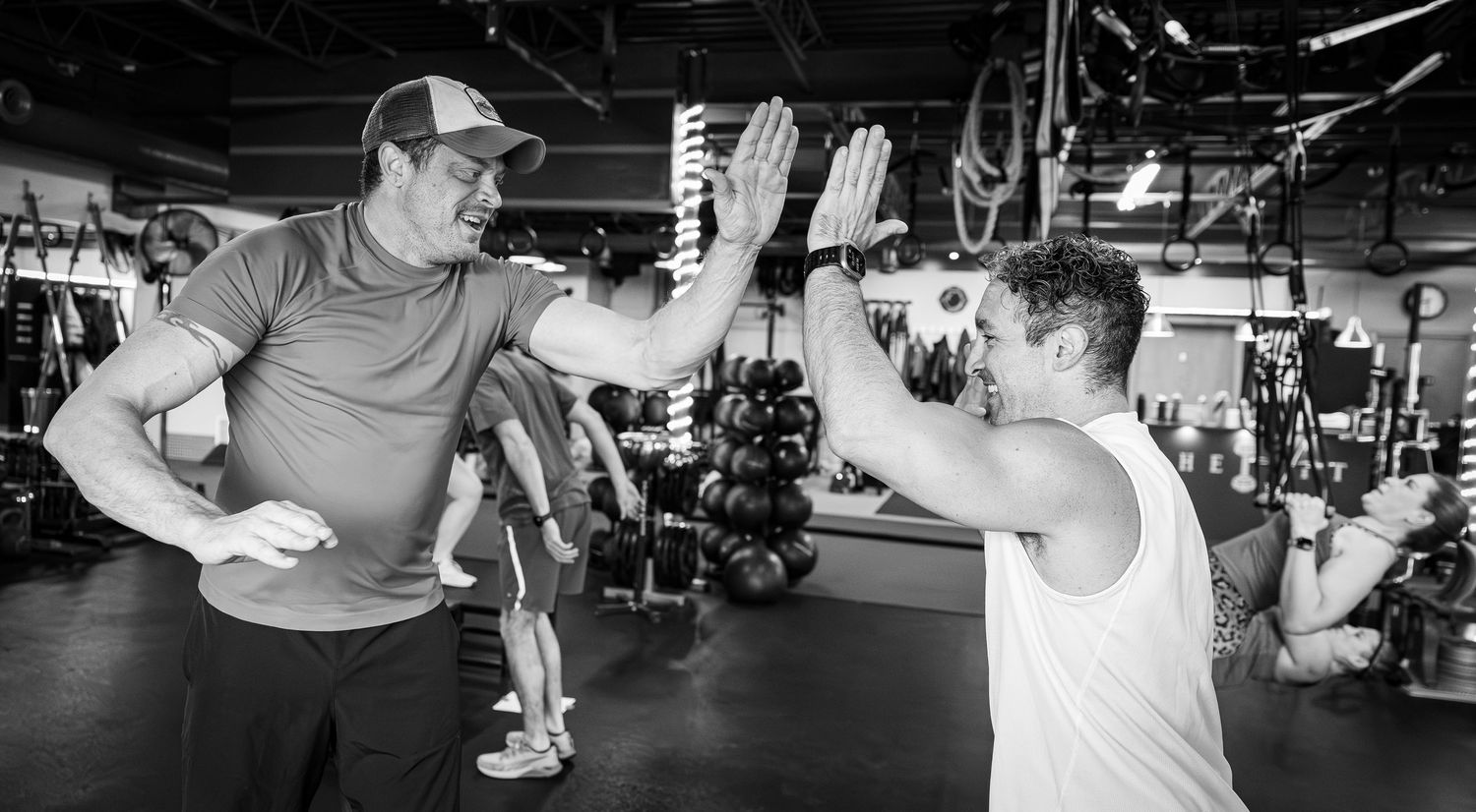 Two men high-fiving in a gym, celebrating a successful workout session together.