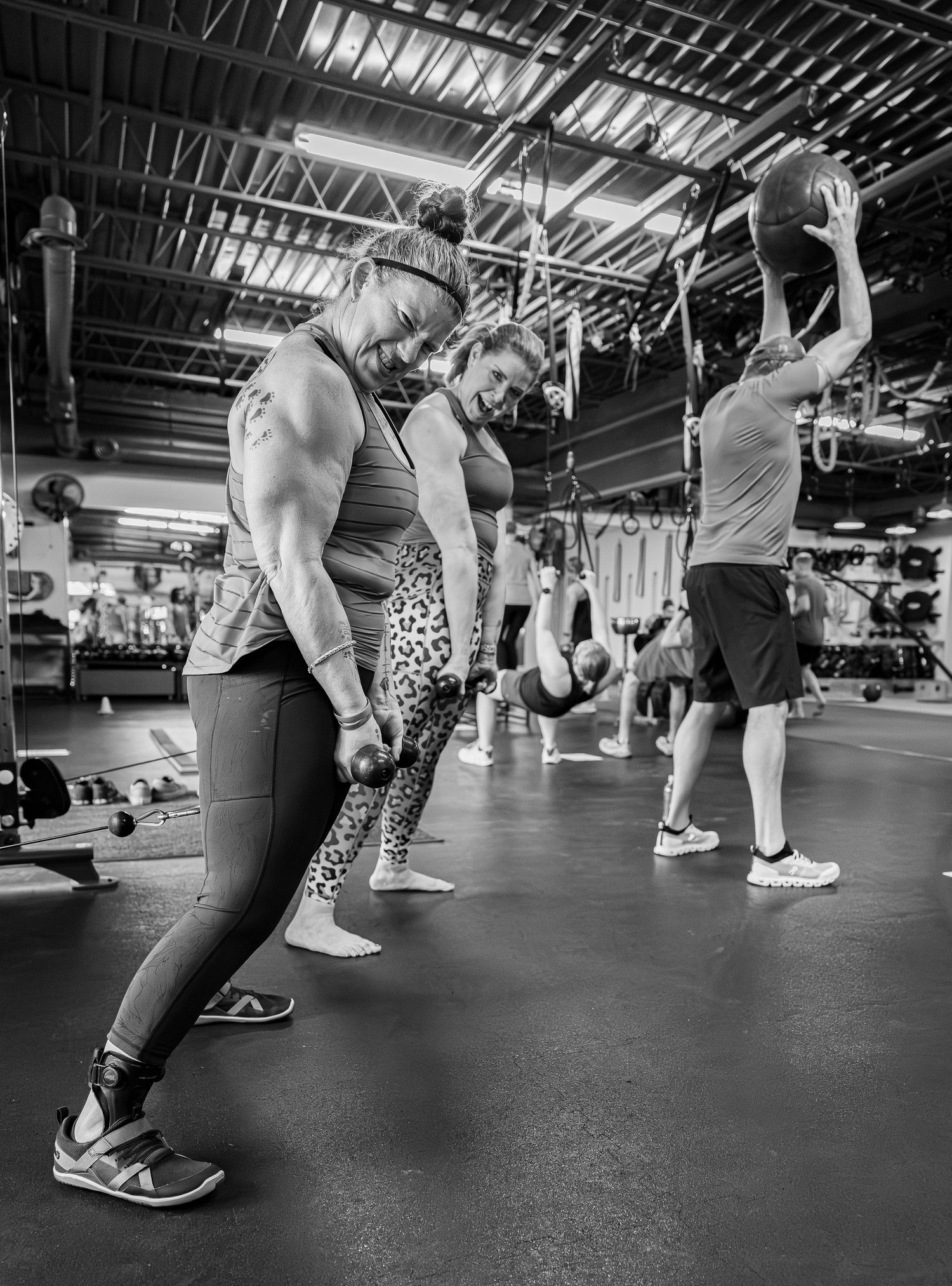 Black and white photo of a group of people lifting weights in a gym class.