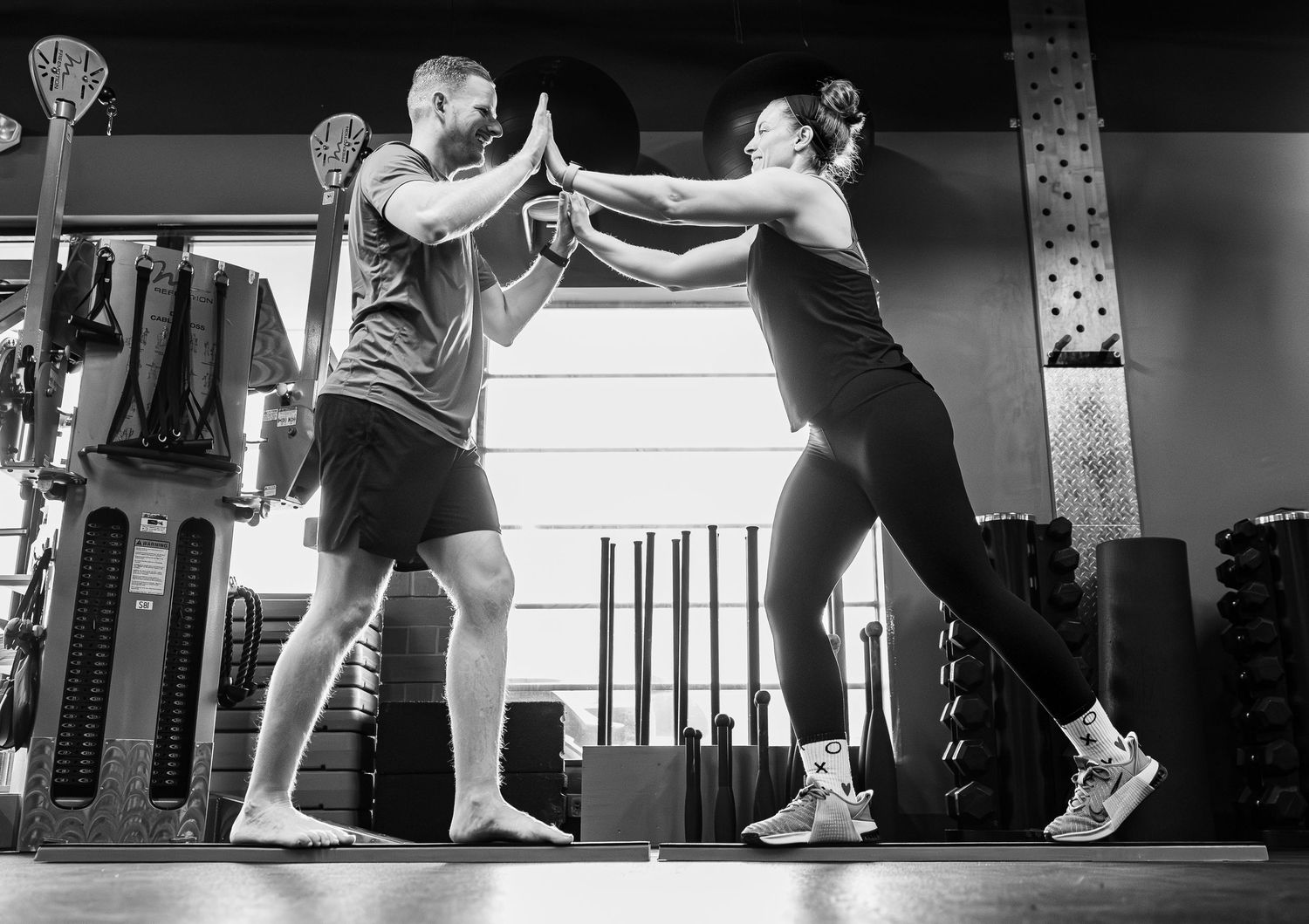 Black and white photo of two gym partners giving a high five after training.