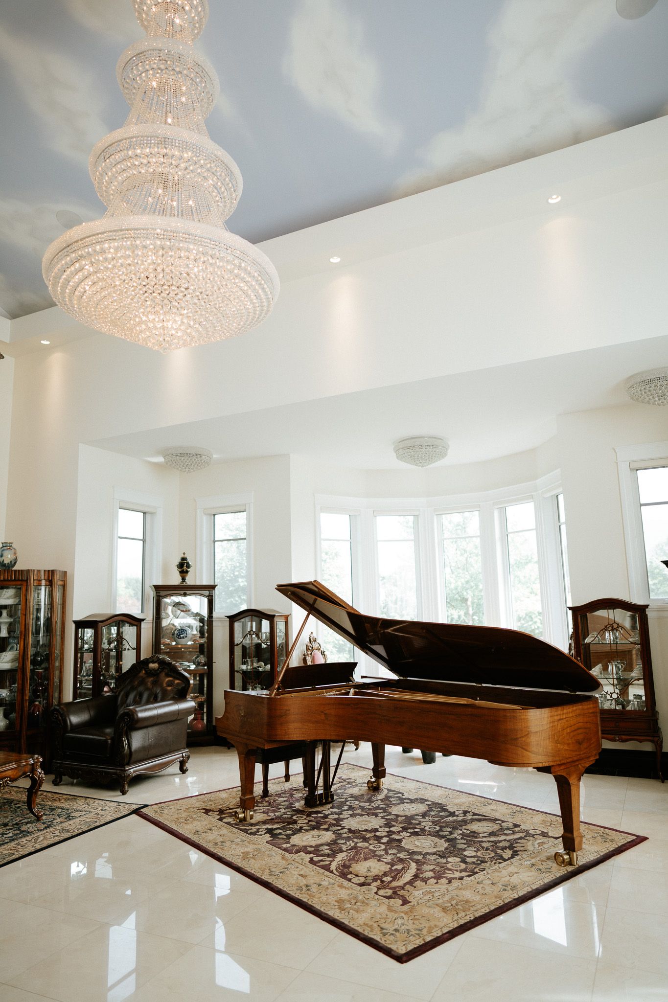 Luxury living room with grand piano, crystal chandelier, and cloud-painted ceiling in elegant decor.