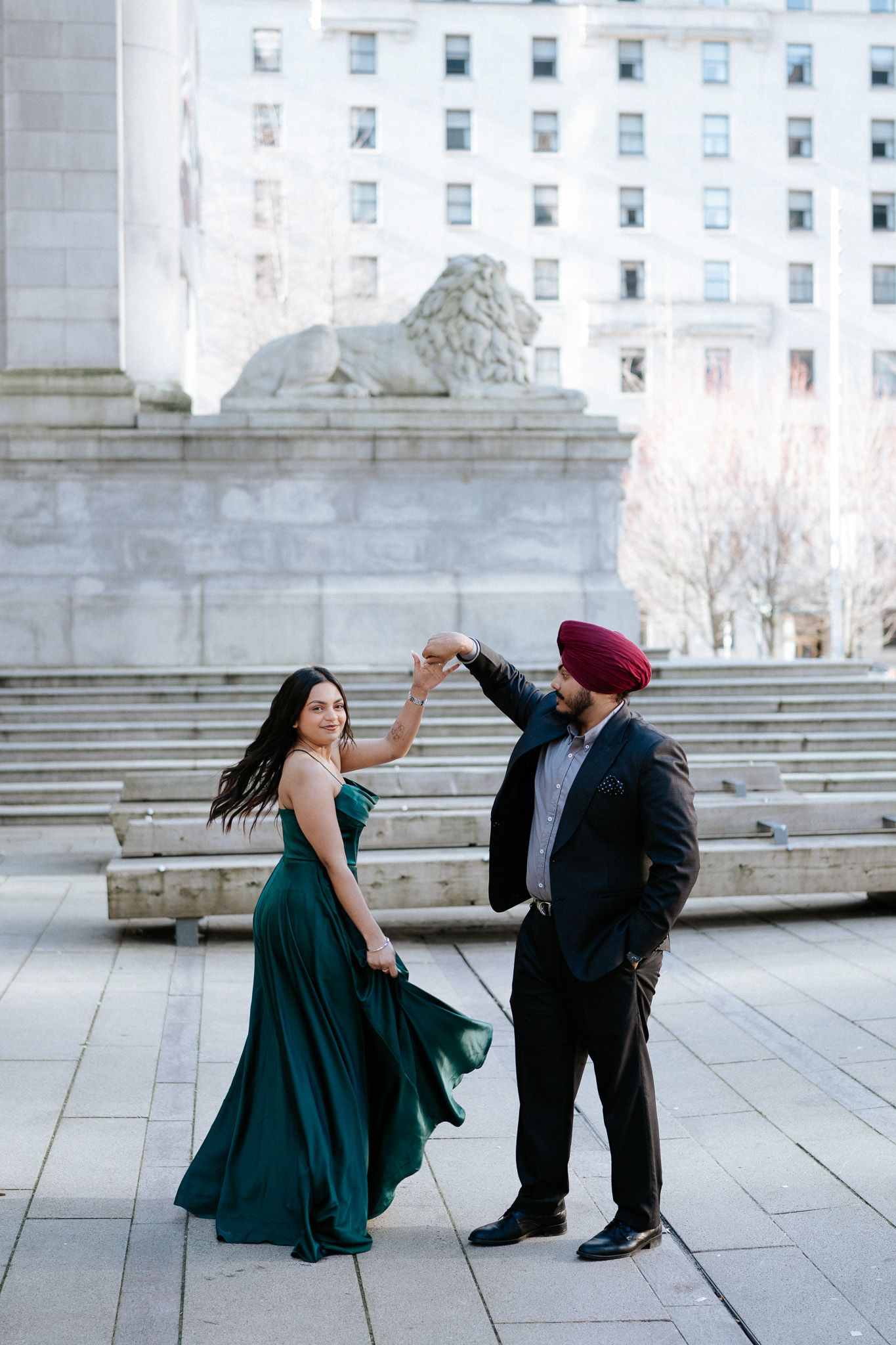 A couple performs a playful dance sequence in front of a neoclassical building with stone steps.