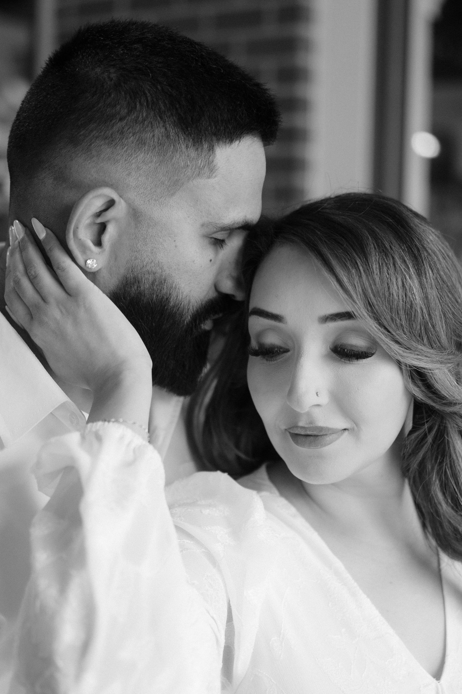 A black and white intimate portrait of a couple in white clothing.