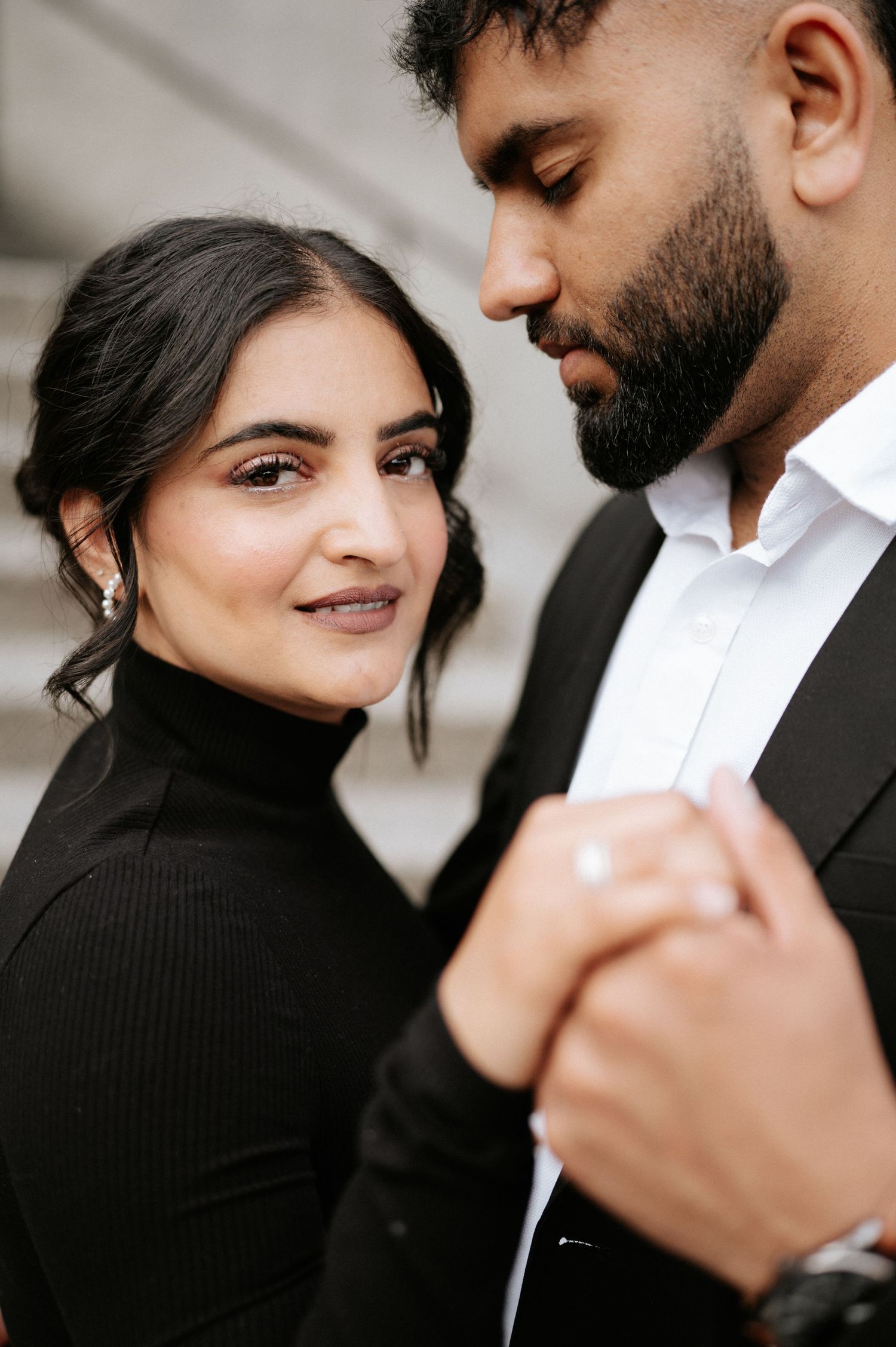 An intimate portrait of a couple in black and white formal wear sharing a tender moment.