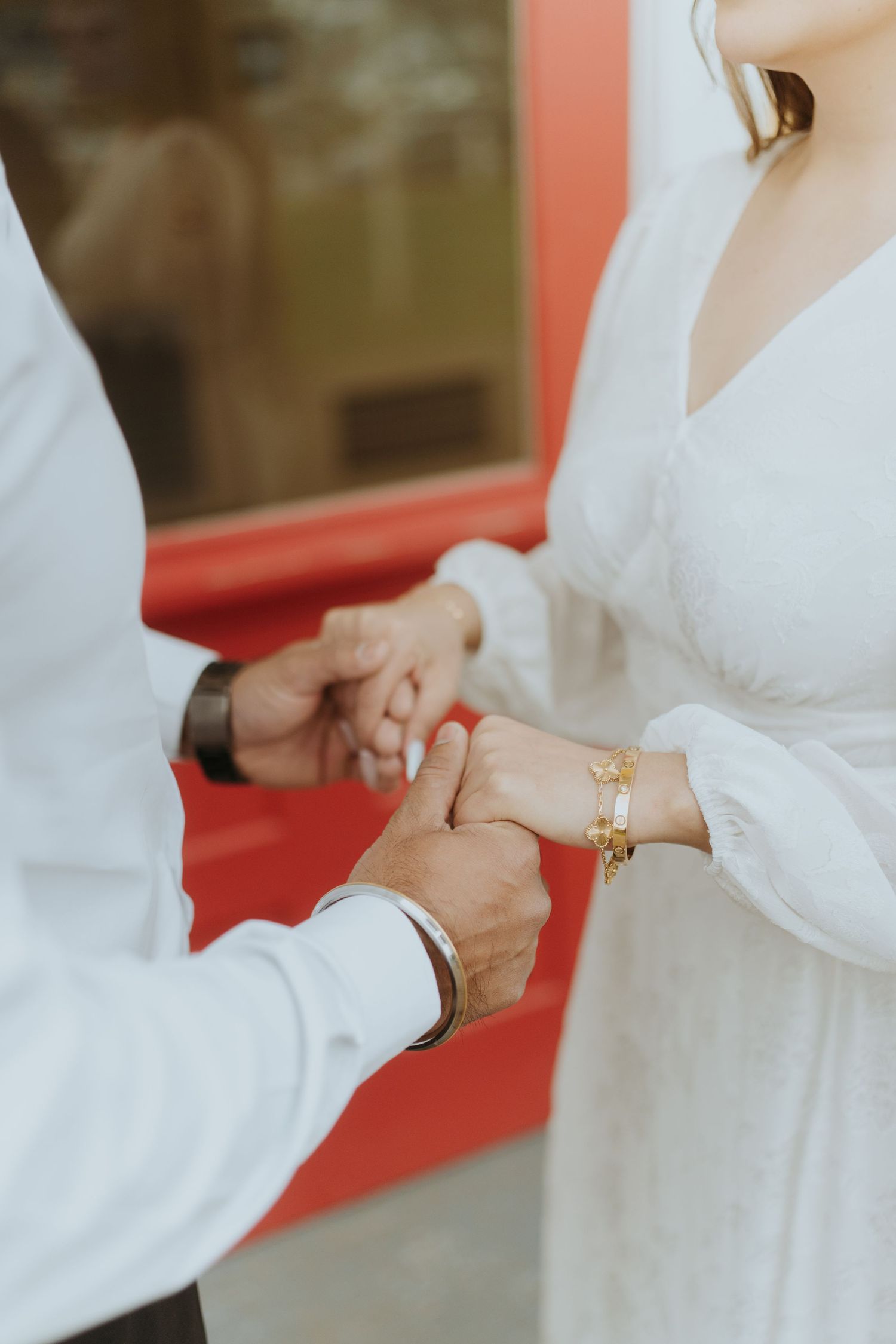 Close-up of hands exchanging rings in white formal attire.