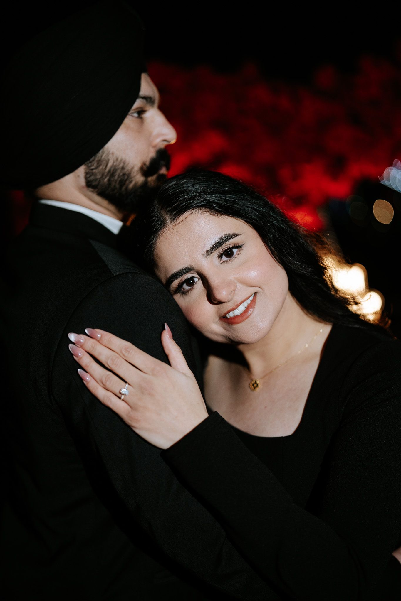 Romantic engagement photo series with dark background and red lighting accents.