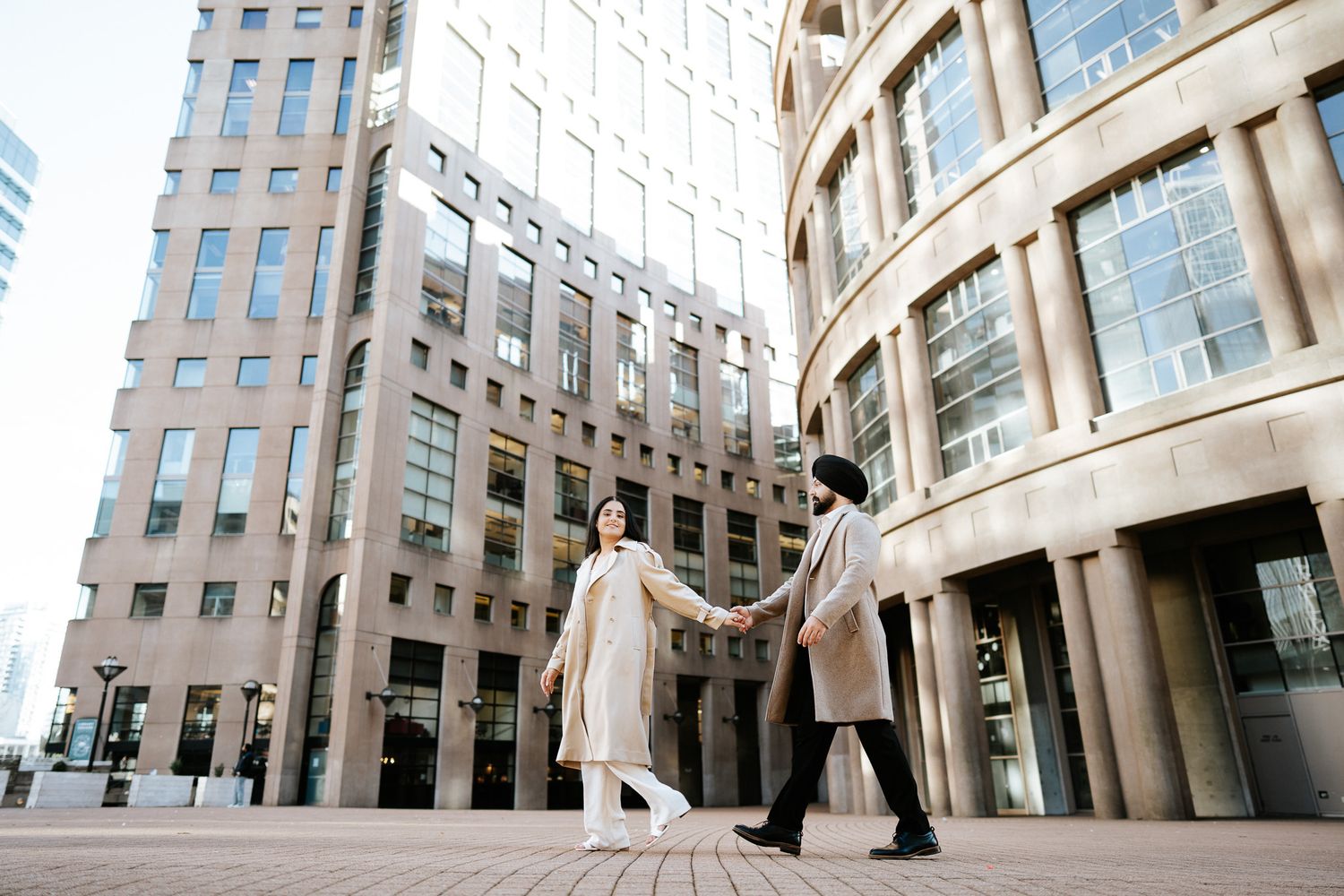 Modern architectural detail of curved glass and stone office building facade with columns and windows in urban setting.