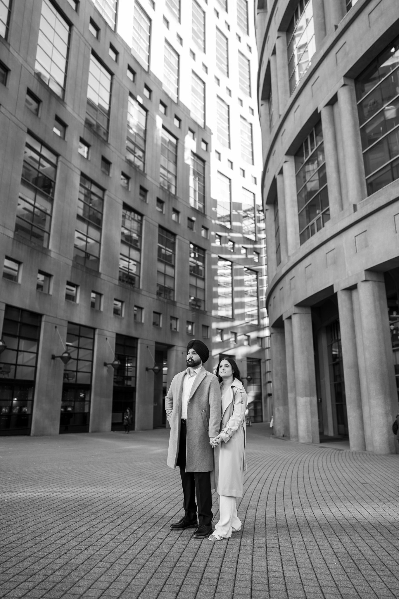 A series of black and white photos showing two figures walking through a modern architectural corridor with curved walls.