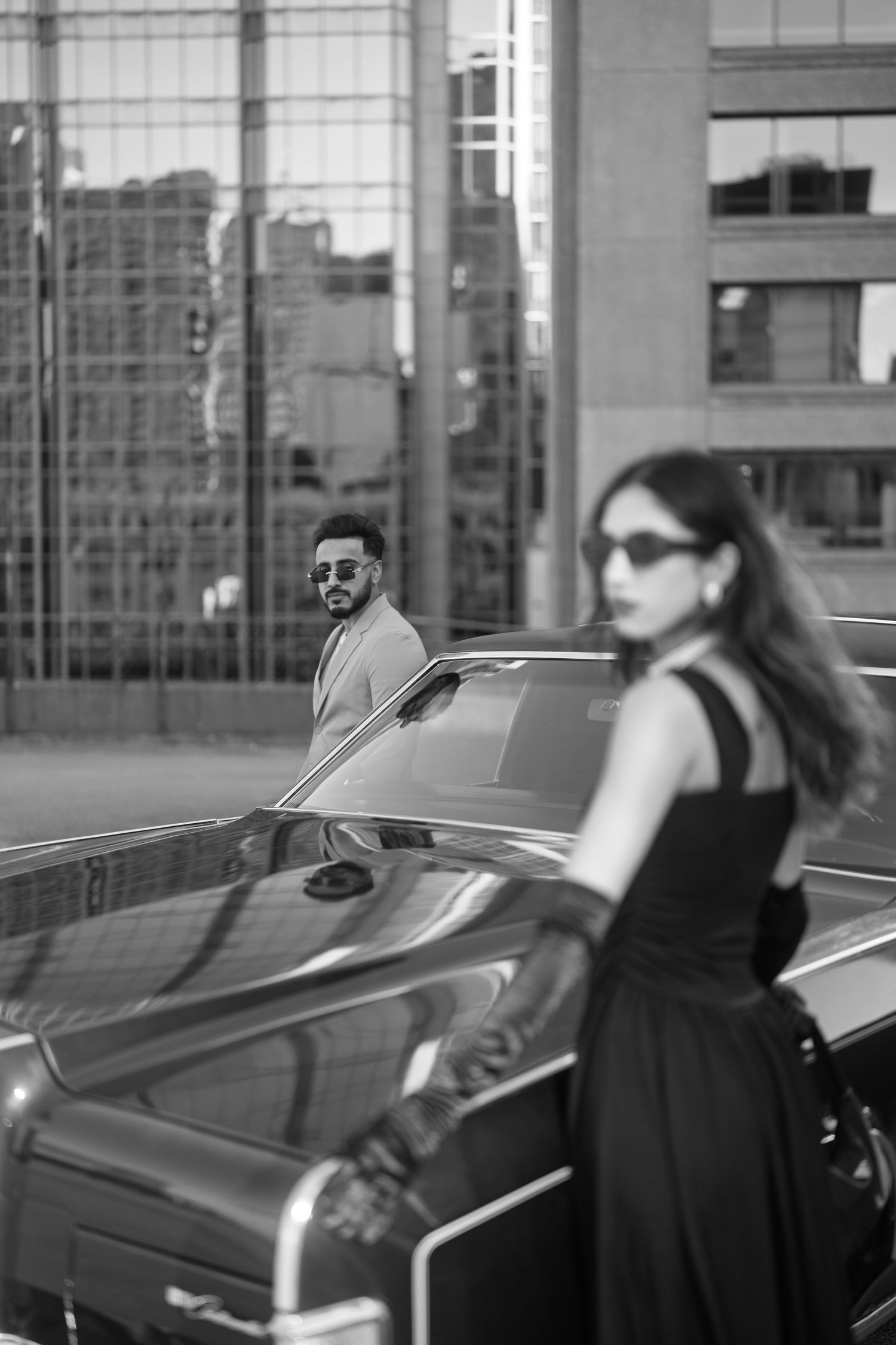 A black and white photo series showing a person in sunglasses getting into a vintage car on a city street.